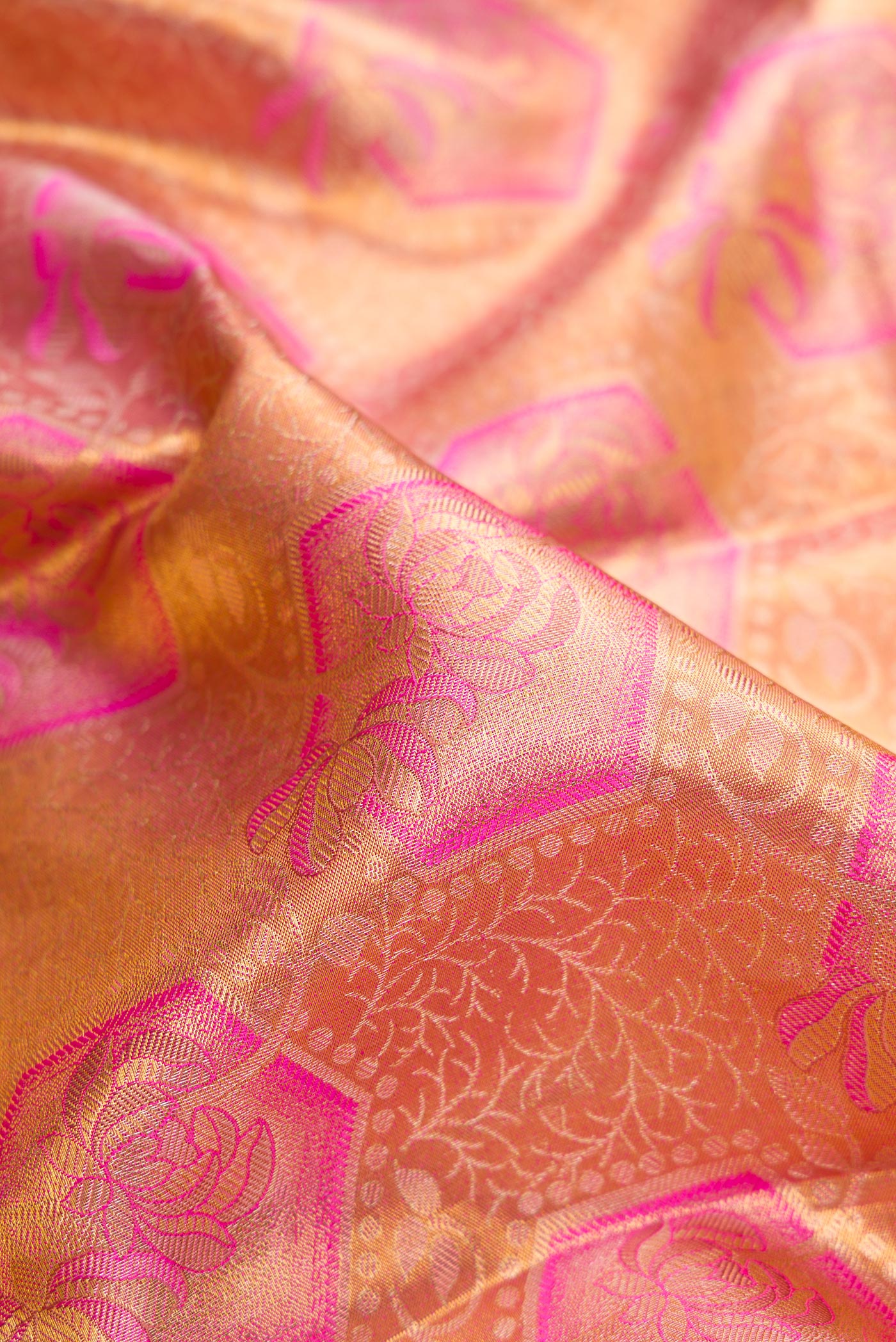 Close up of Peach Dual Tone Kanchipuram Tissue Silk Saree with Zari Brocade on the body and Fancy Border.  displaying folds