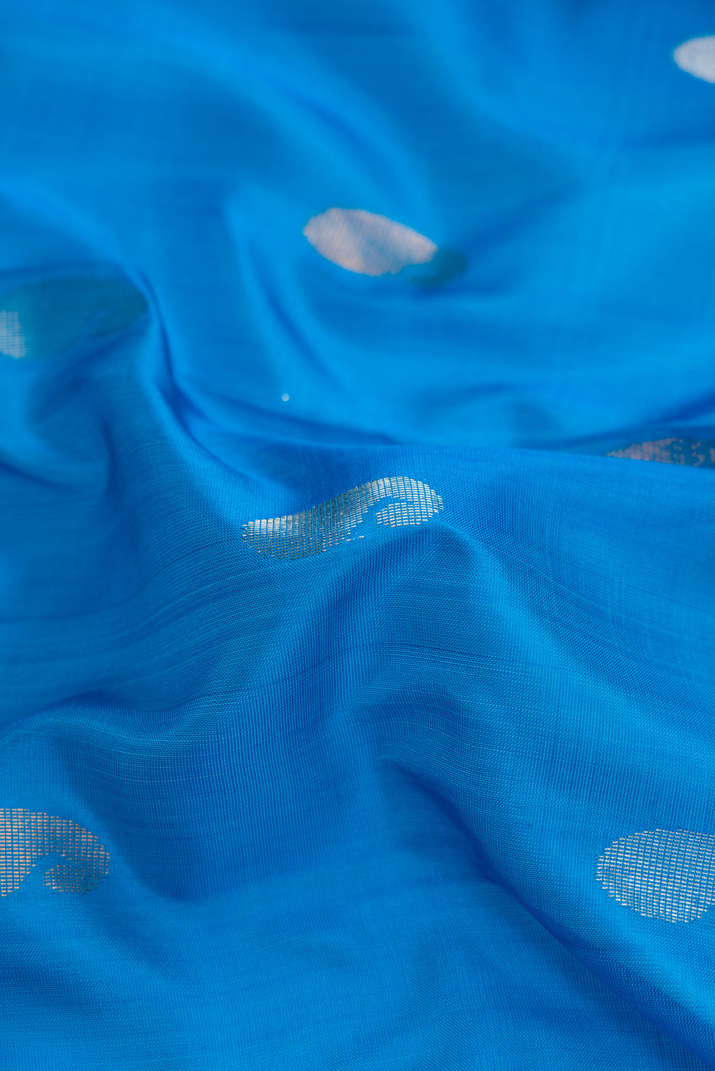 Close up of Peacock Blue Dual Tone Uppada Silk Saree with Zari Butta on the body and Zari Border.  displaying folds