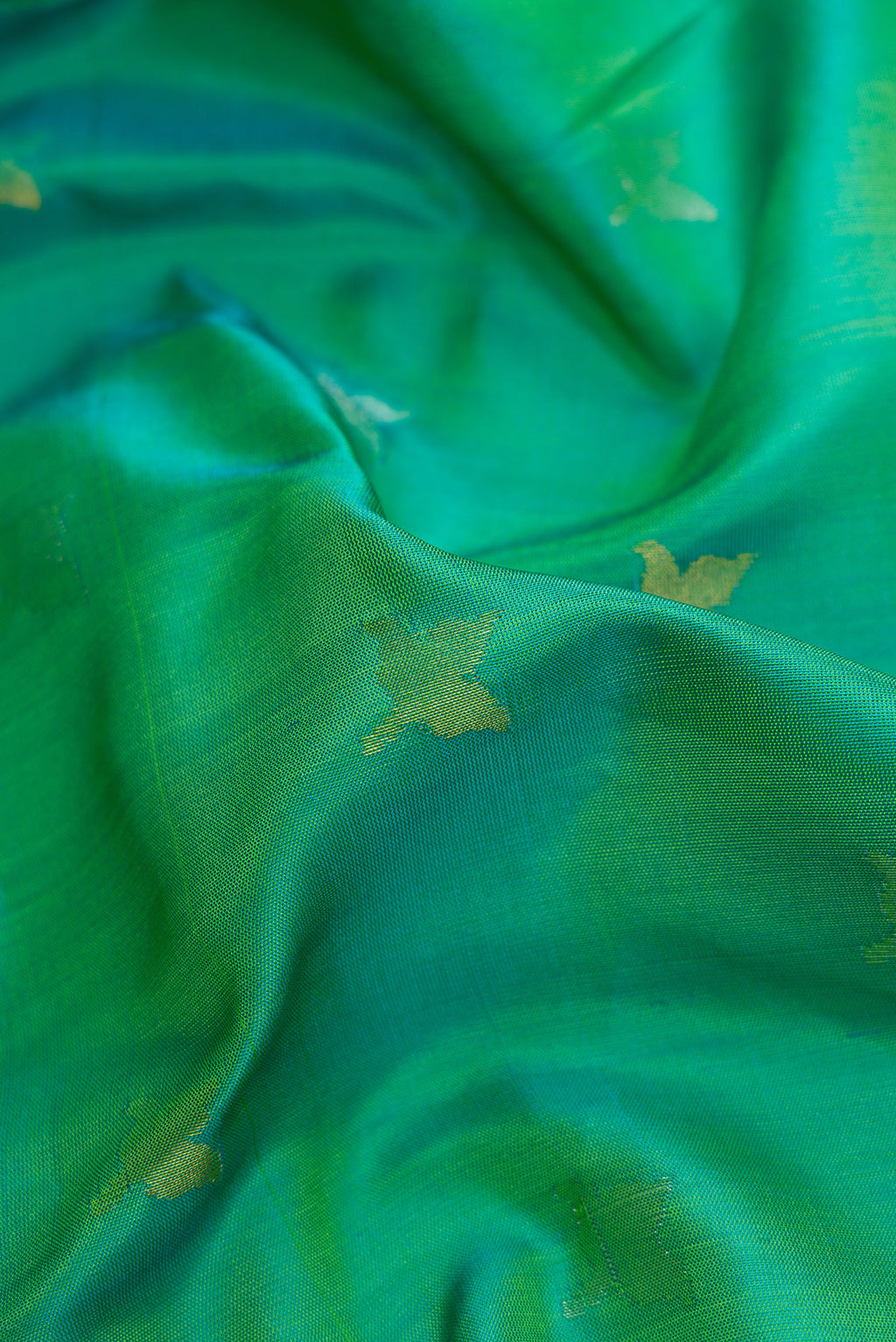Close up of Green Dual Tone Uppada Silk Saree with Zari Butta on the body and Zari Border.  displaying folds