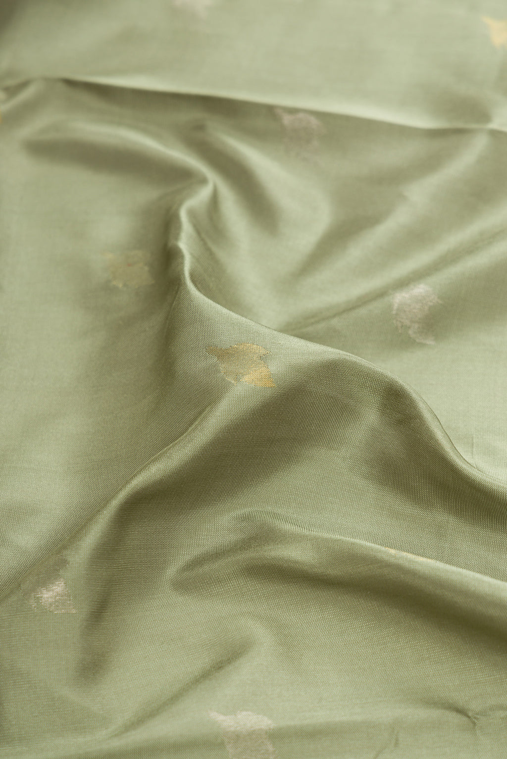 Close up of Light Green Dual Tone Soft Silk Saree with Zari Butta on the body and Zari Border.  displaying folds