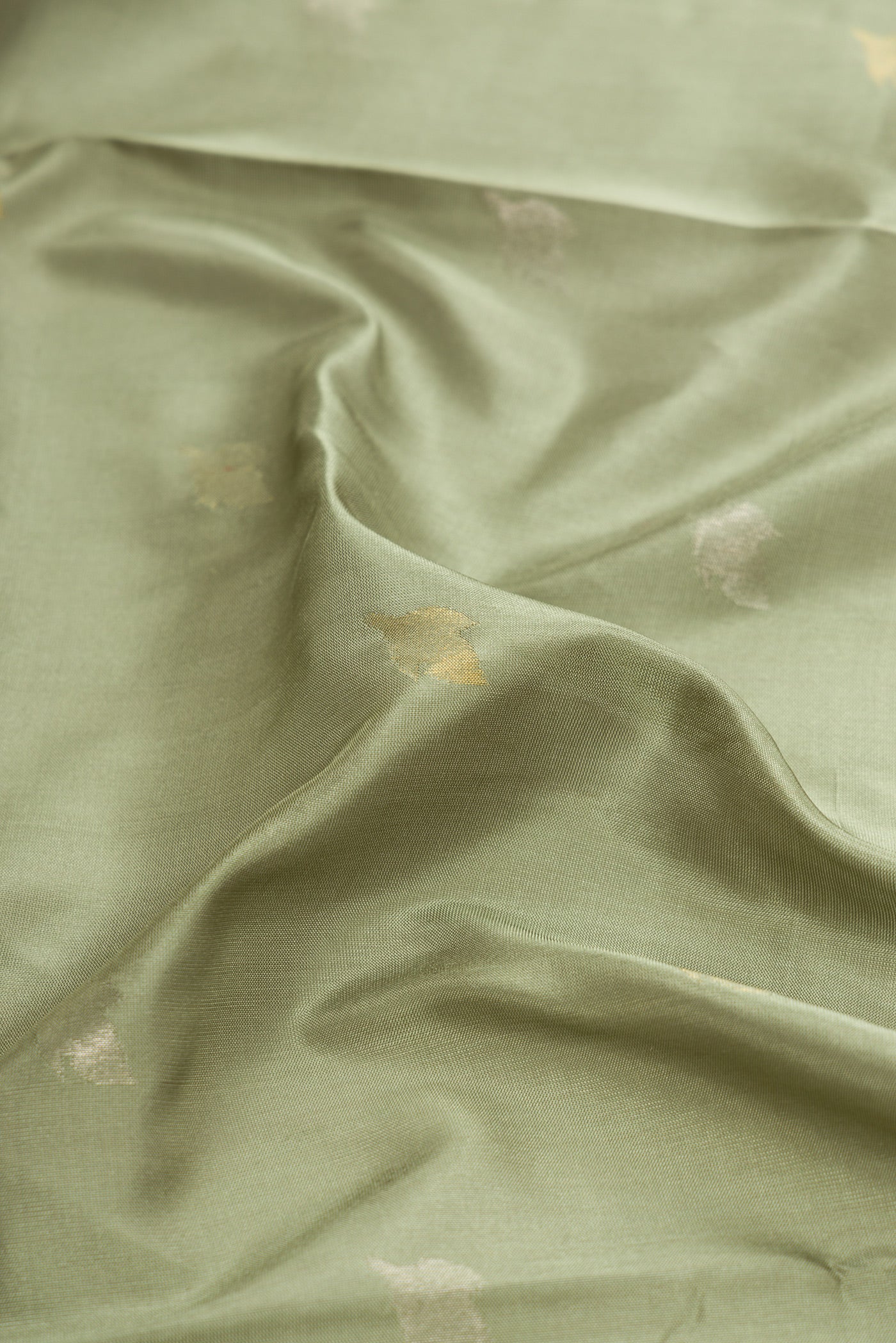 Close up of Light Green Dual Tone Soft Silk Saree with Zari Butta on the body and Zari Border.  displaying folds