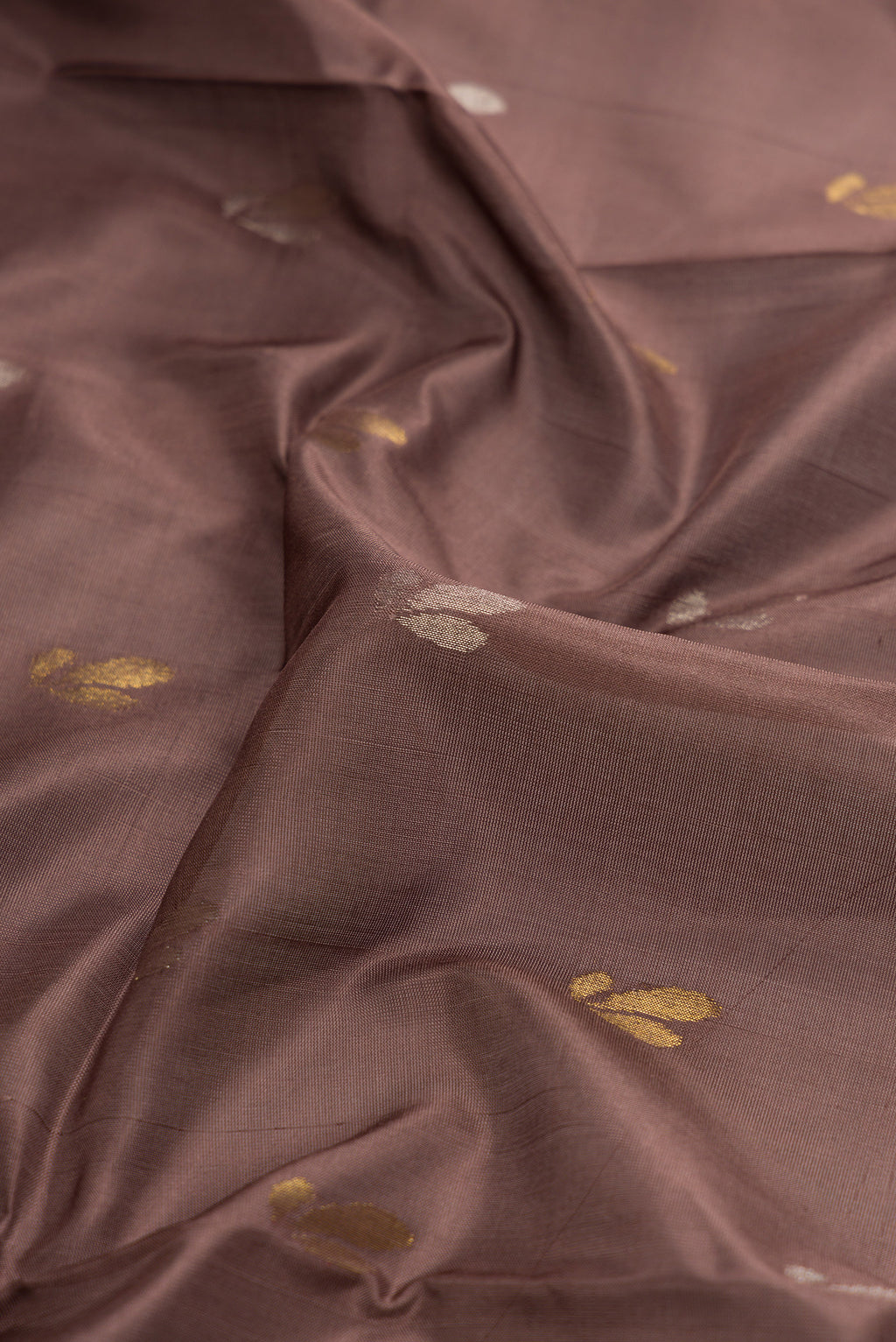 Close up of Brown Dual Tone Soft Silk Saree with Zari Butta on the body and Zari Border.  displaying folds