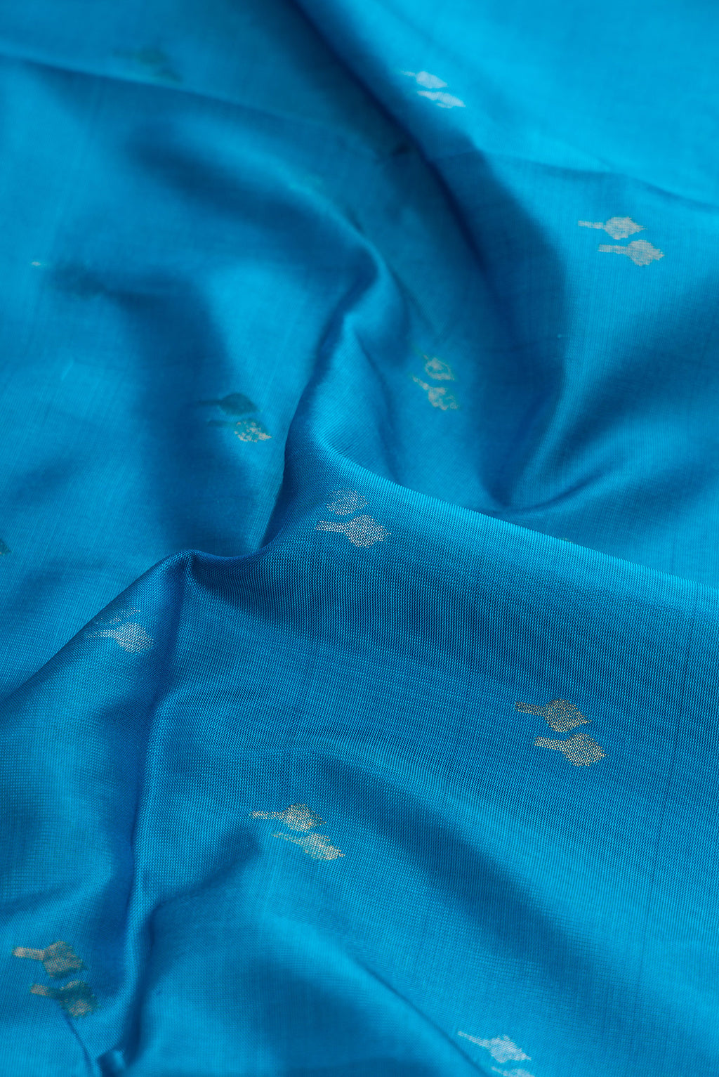 Close up of Sky Blue Dual Tone Soft Silk Saree with Zari Butta on the body and Zari Border.  displaying folds