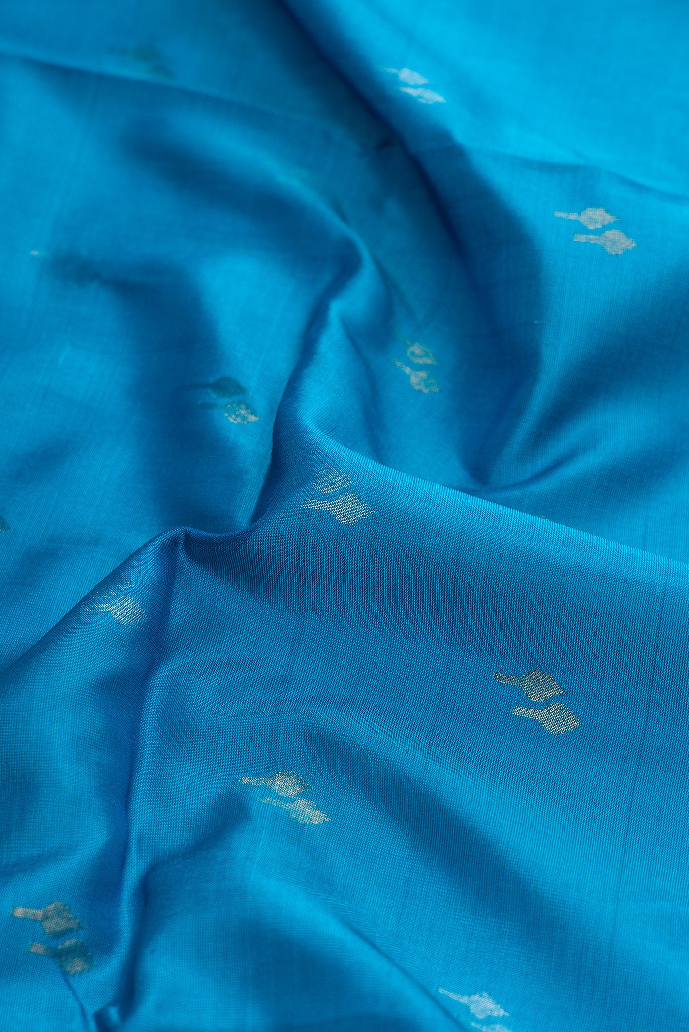 Close up of Sky Blue Dual Tone Soft Silk Saree with Zari Butta on the body and Zari Border.  displaying folds