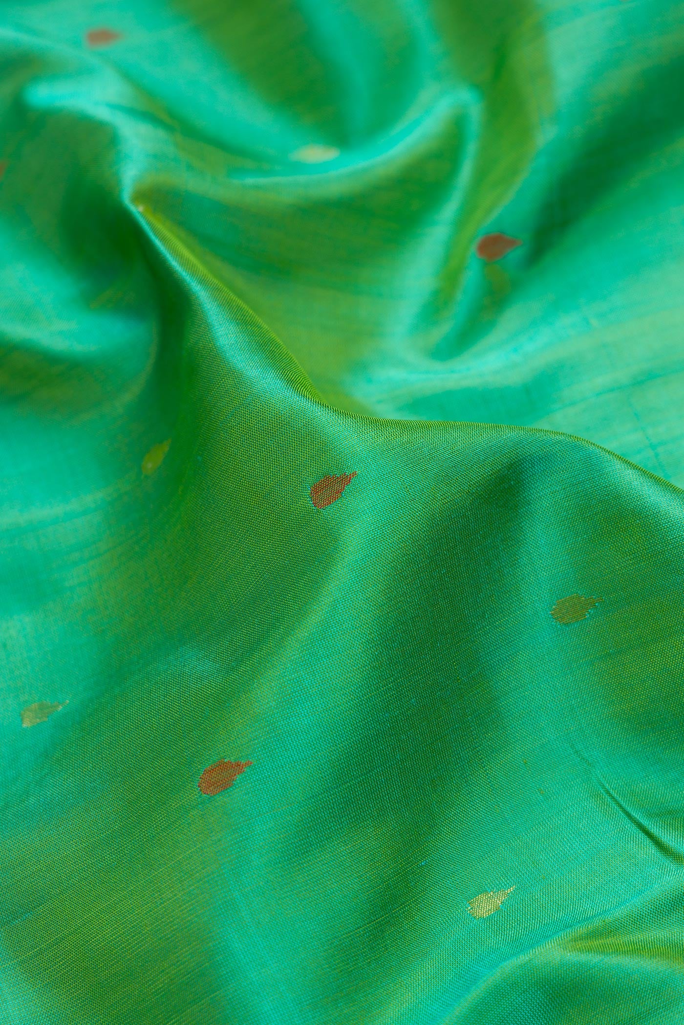 Close up of Green Dual Tone Uppada Silk Saree with Zari Butta on the body and Zari Border.  displaying folds