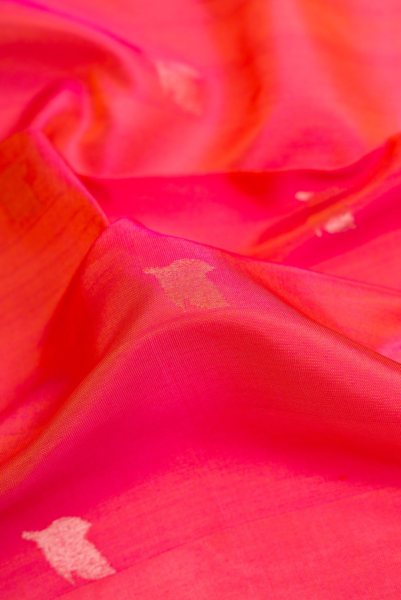Close up of Coral Dual Tone Uppada Silk Saree with Zari Butta on the body and Zari Border.  displaying folds