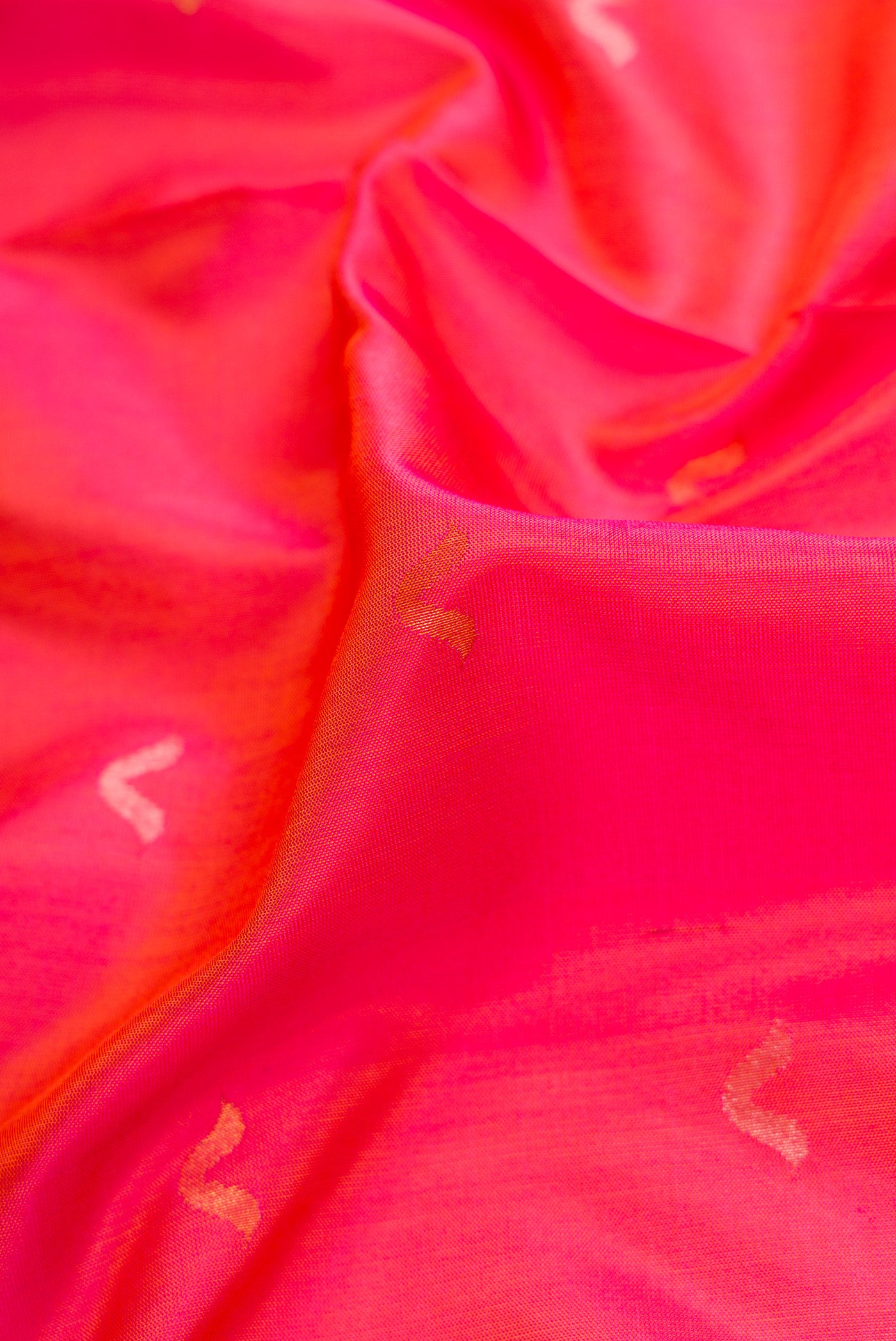 Close up of Coral Dual Tone Uppada Silk Saree with Zari Butta on the body and Zari Border.  displaying folds