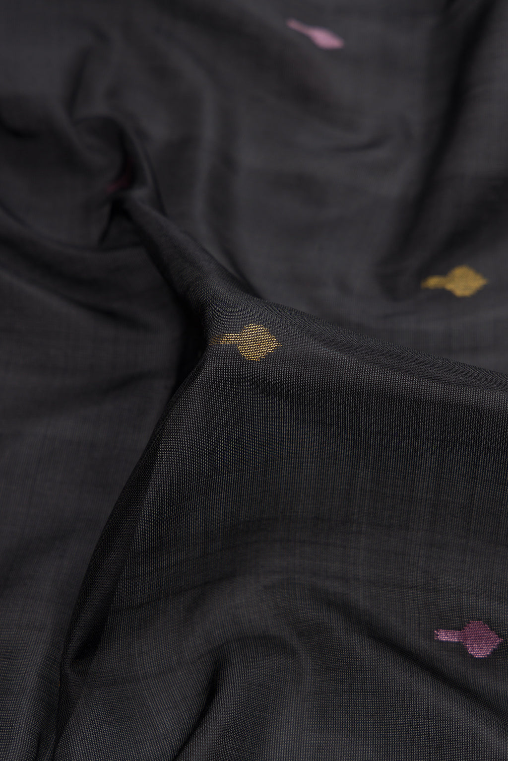 Close up of Black Dual Tone Uppada Silk Saree with Zari And Thread Butta on the body and Zari Border.  displaying folds