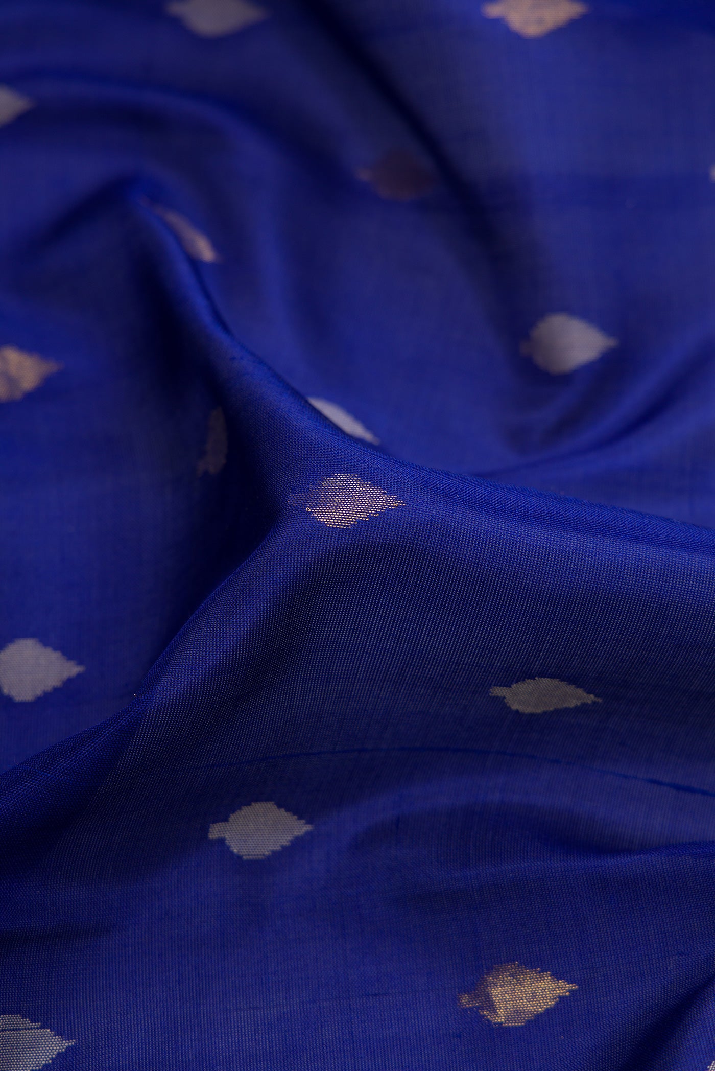 Close up of Navy Blue Dual Tone Uppada Silk Saree with Zari Butta on the body and Temple Border.  displaying folds