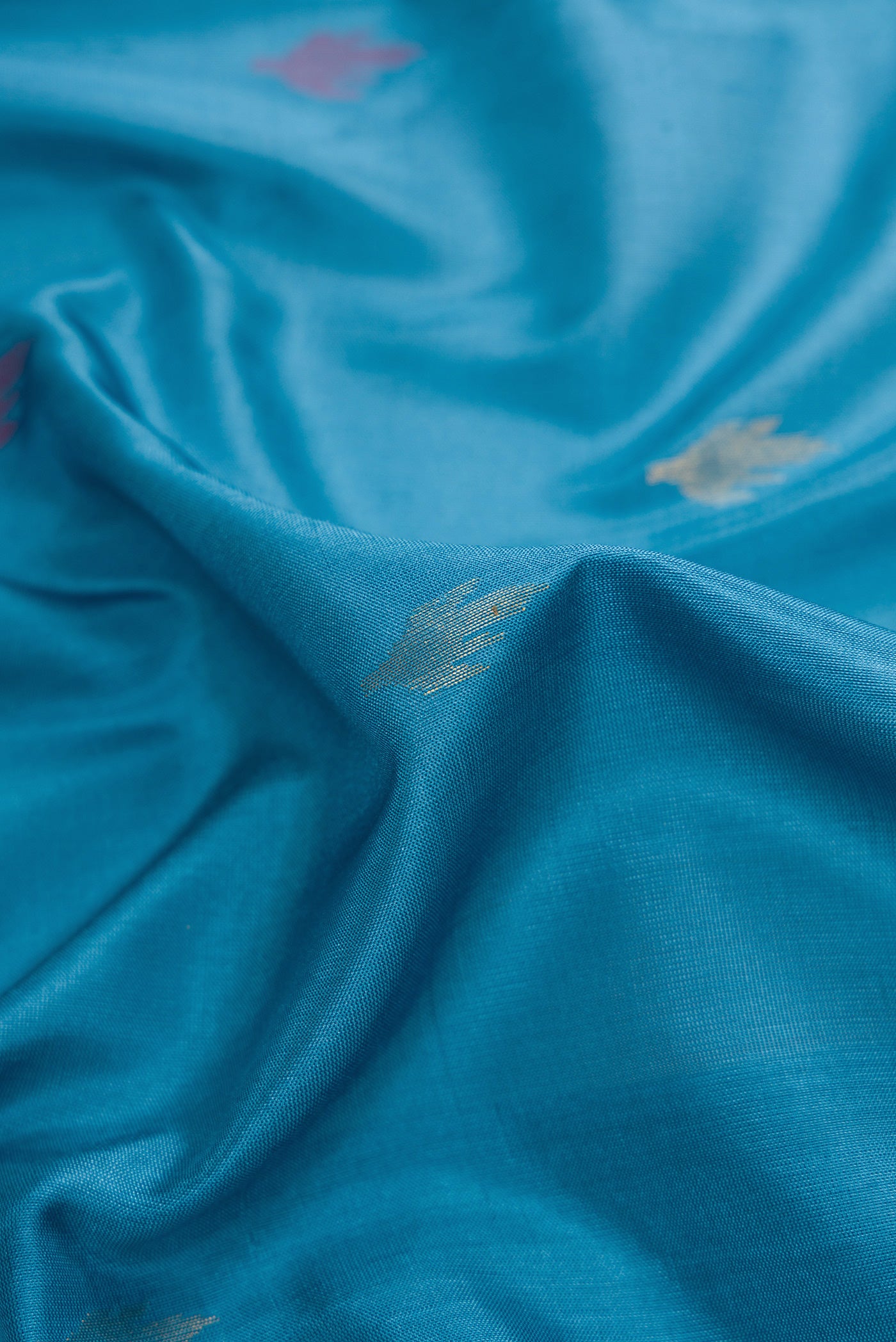Close up of Sky Blue Dual Tone Uppada Silk Saree with Zari And Thread Butta on the body and Fancy Border.  displaying folds