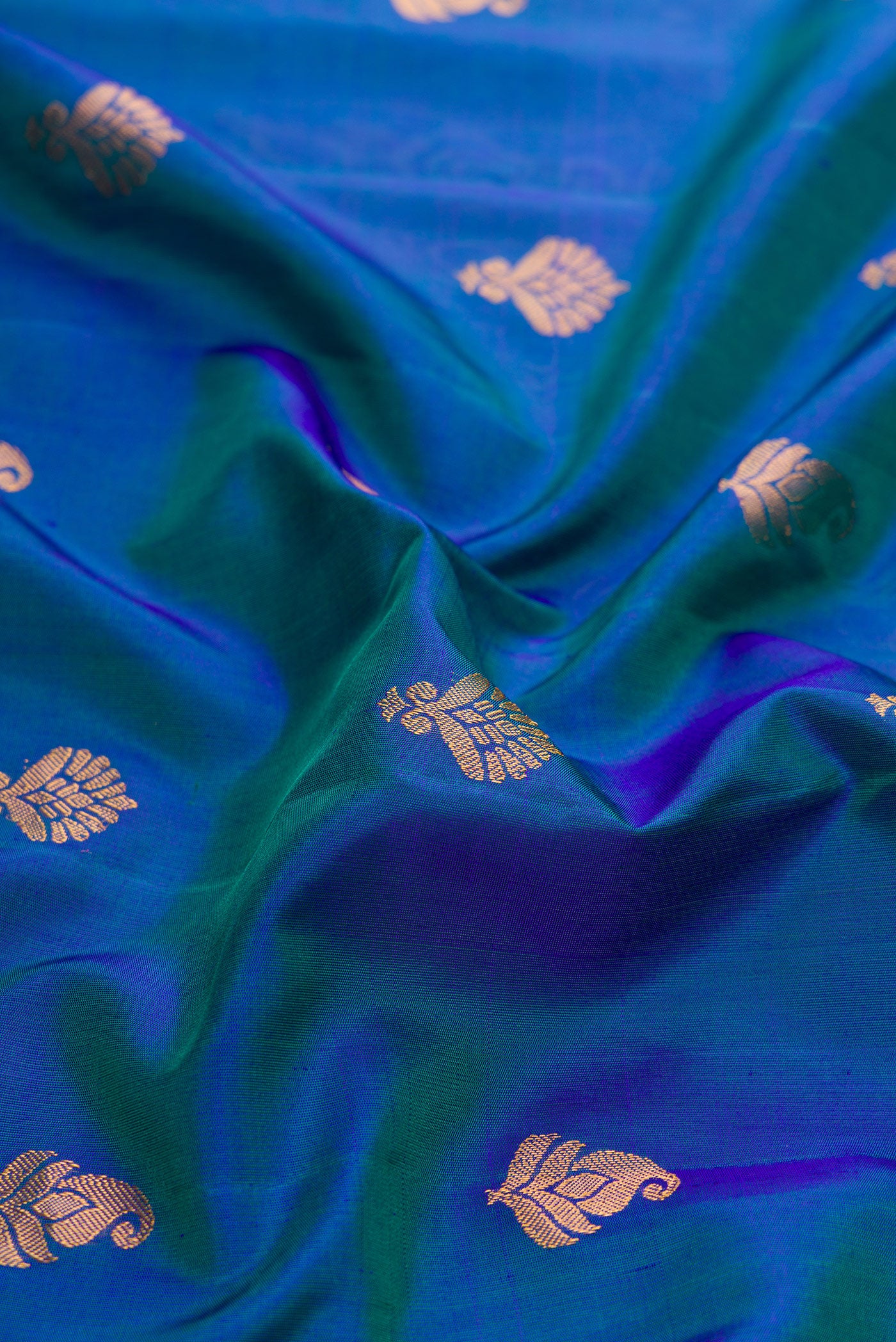 Close up of Peacock Blue Dual Tone Gadwal Silk Saree with Zari Butta on the body and Zari And Thread Border.  displaying folds