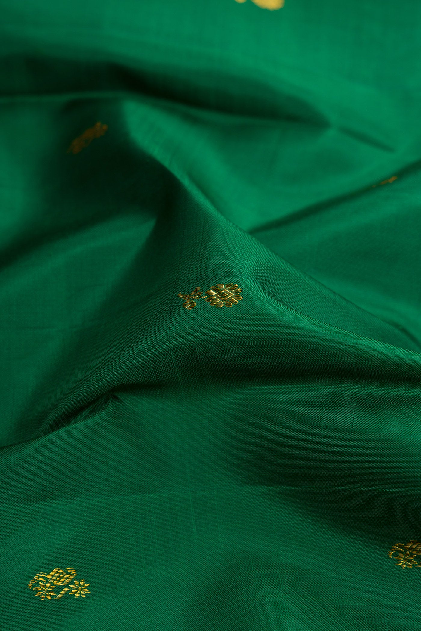 Close up of Green Dual Tone Kanjivaram Silk Saree with Zari Butta on the body and Zari Border.  displaying folds