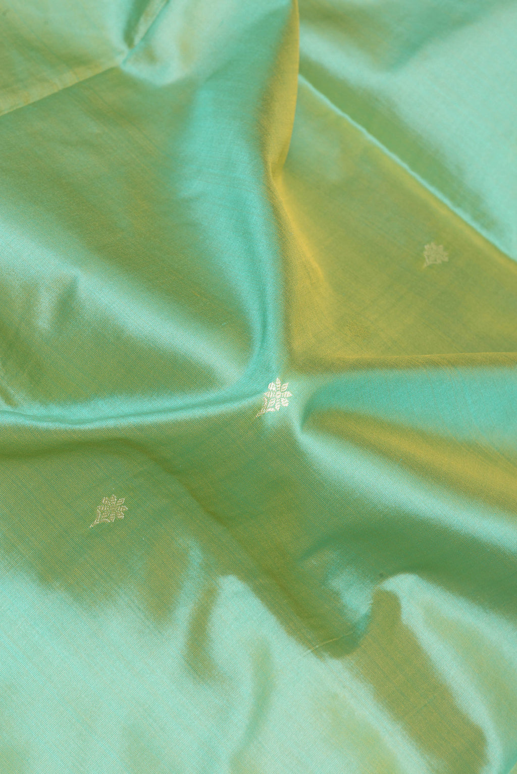 Close up of Light Green Banarasi Silk Saree with Thread Butta on the body and Thread Border.  displaying folds