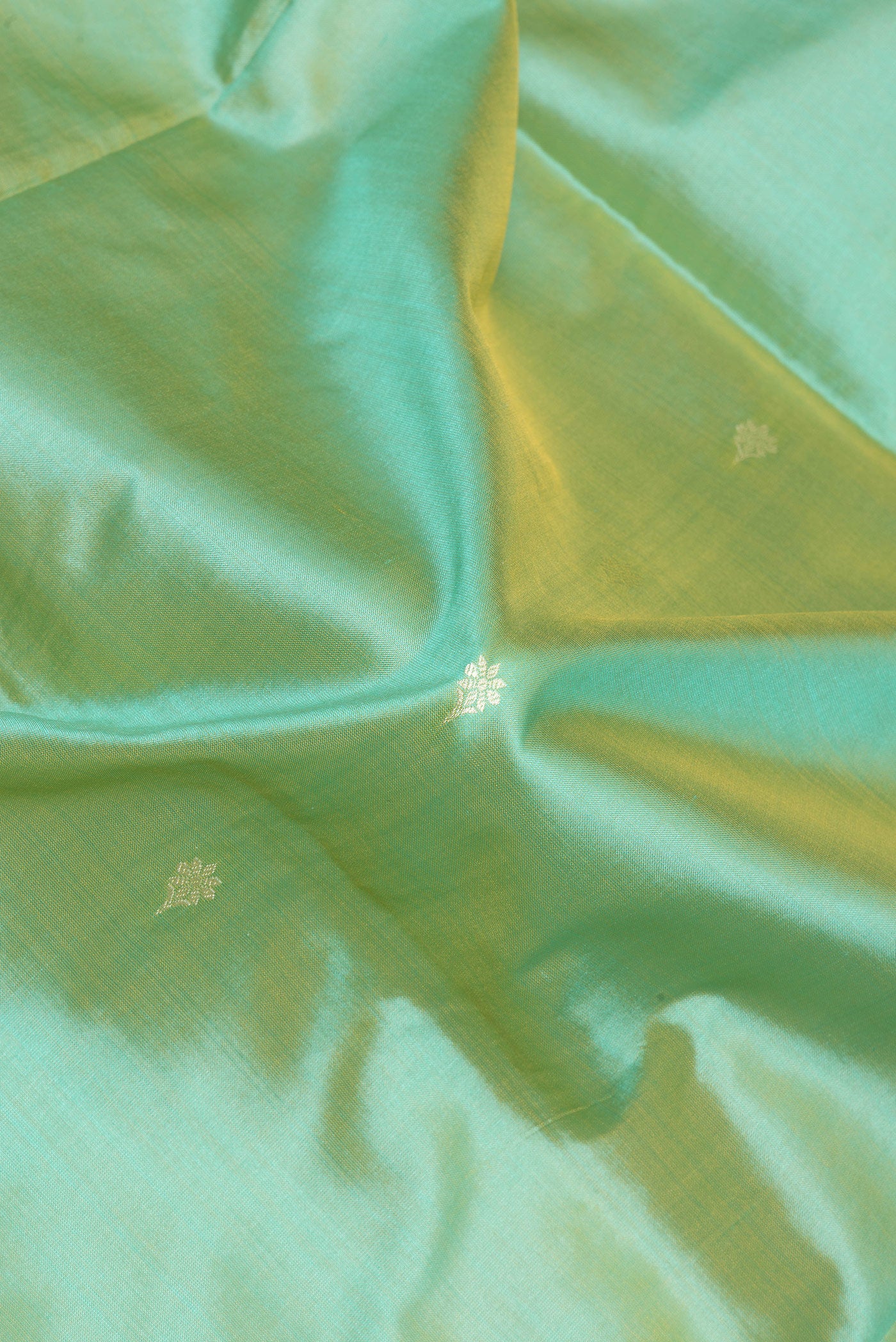 Close up of Light Green Banarasi Silk Saree with Thread Butta on the body and Thread Border.  displaying folds