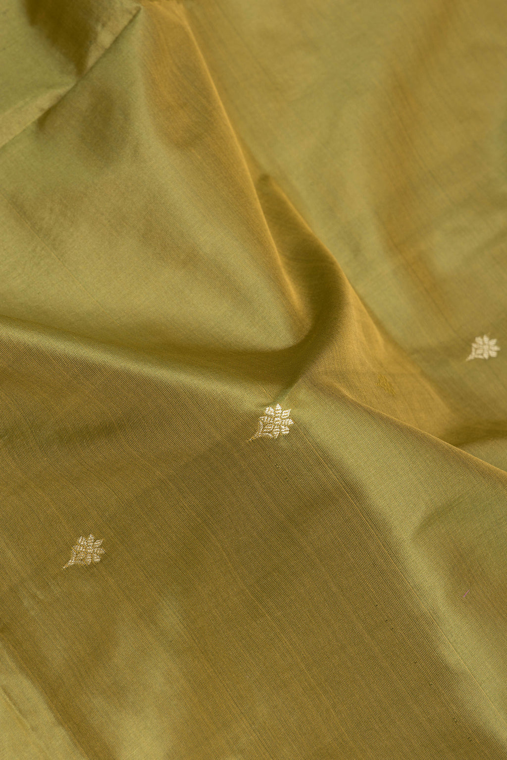 Close up of Mehandi Green Banarasi Silk Saree with Thread Butta on the body and Thread Border.  displaying folds