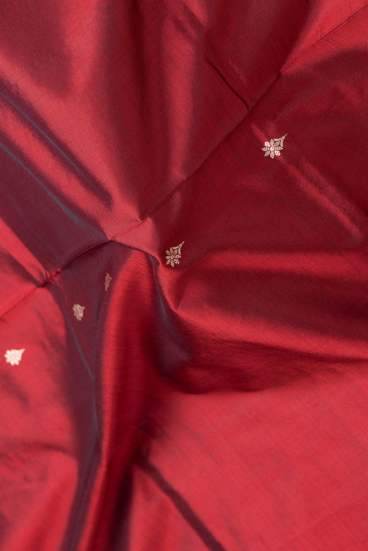 Close up of Maroon Dual Tone Banarasi Silk Saree with Thread Butta on the body and Thread Border.  displaying folds