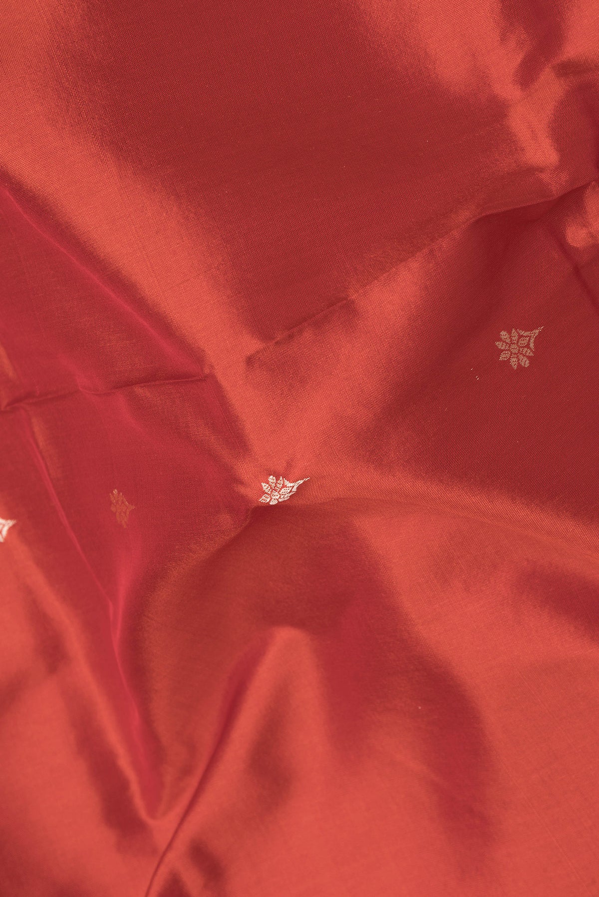 Close up of Brick Orange Dual Tone Banarasi Silk Saree with Thread Butta on the body and Thread Border.  displaying folds