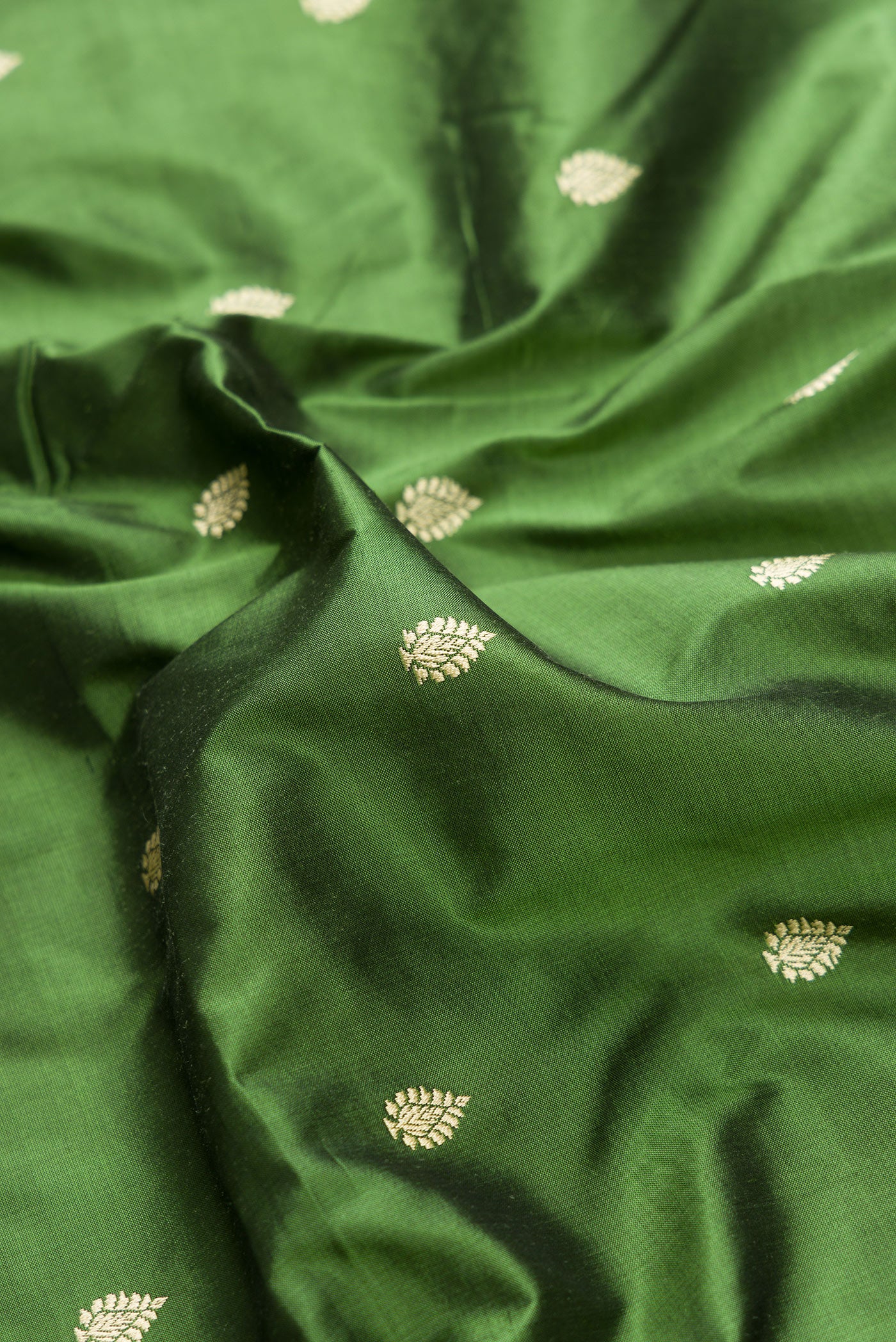 Close up of Green Dual Tone Banarasi Silk Saree with Thread Butta on the body and Thread Border.  displaying folds