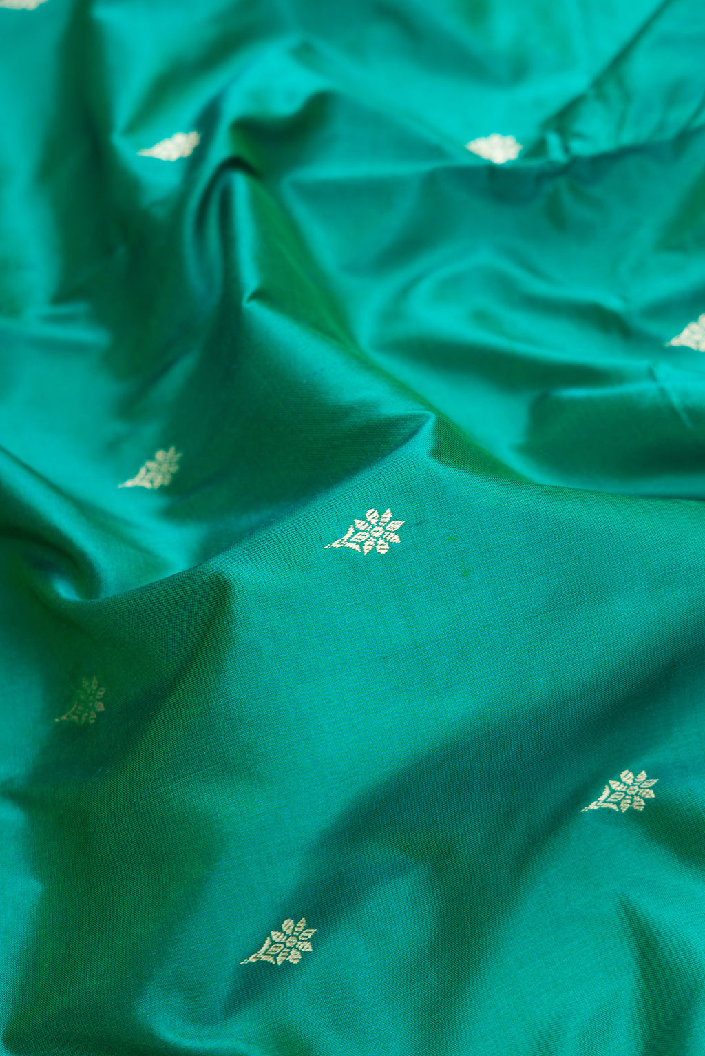 Close up of Peacock Blue Dual Tone Banarasi Silk Saree with Thread Butta on the body and Thread Border.  displaying folds