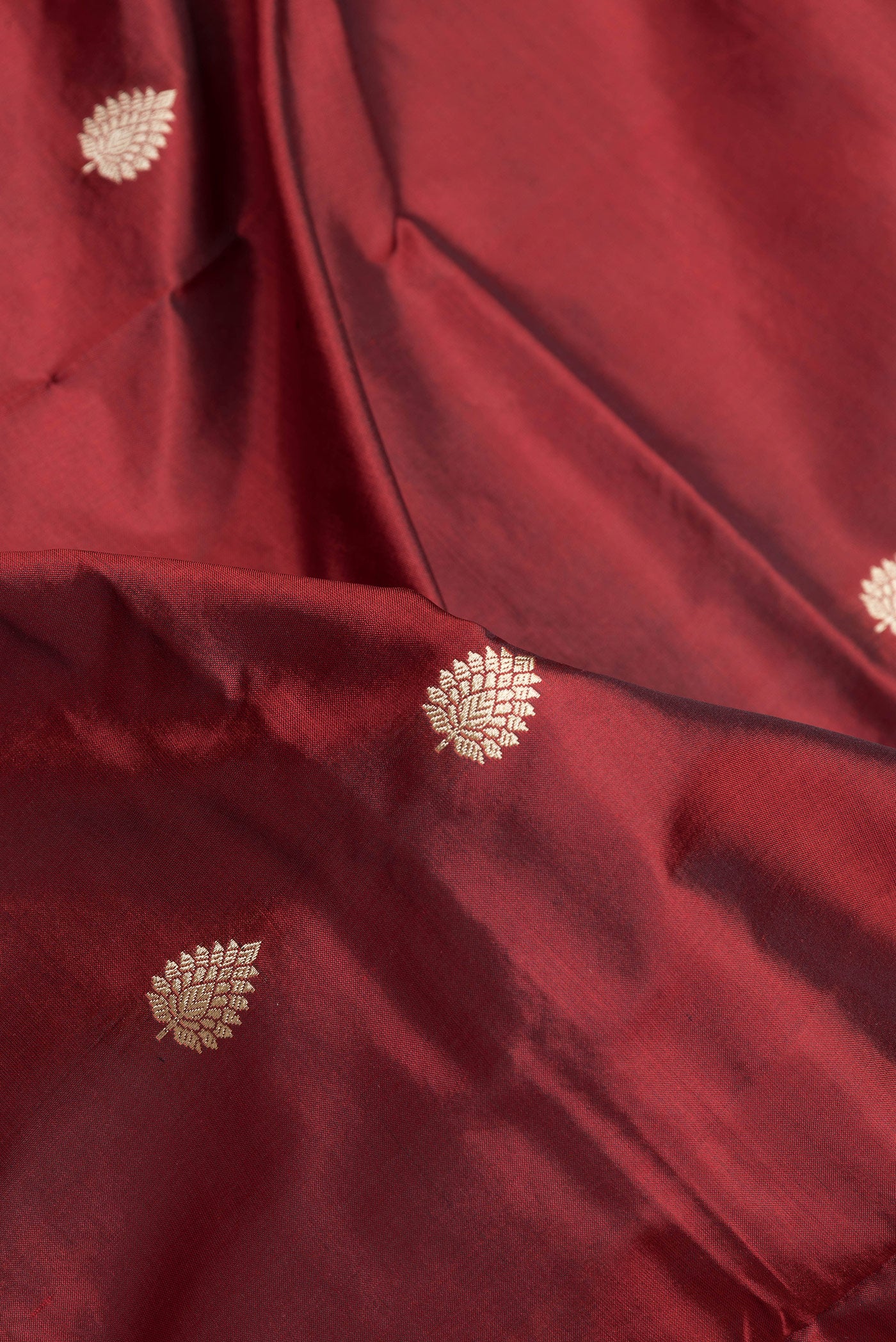 Close up of Maroon Dual Tone Banarasi Silk Saree with Thread Butta on the body and Thread Border.  displaying folds