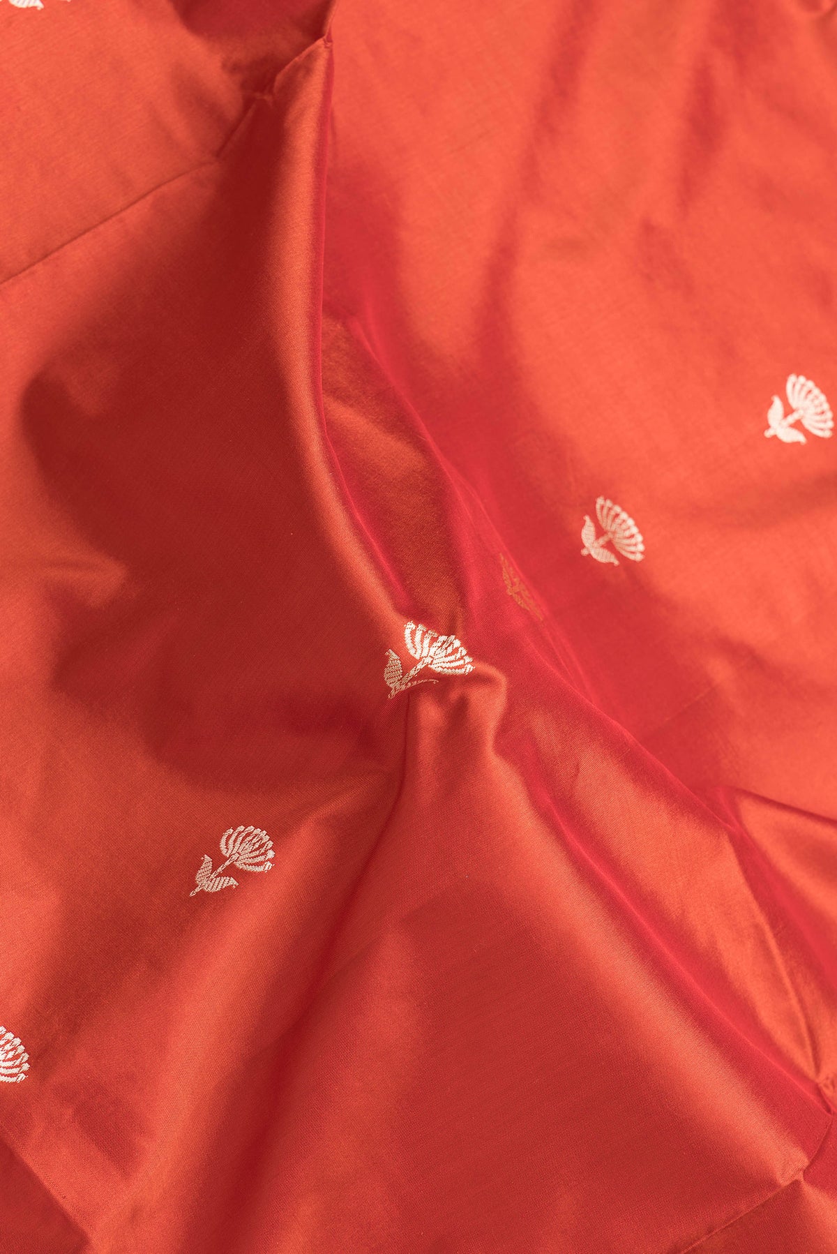 Close up of Red Dual Tone Banarasi Silk Saree with Thread Butta on the body and Thread Border.  displaying folds