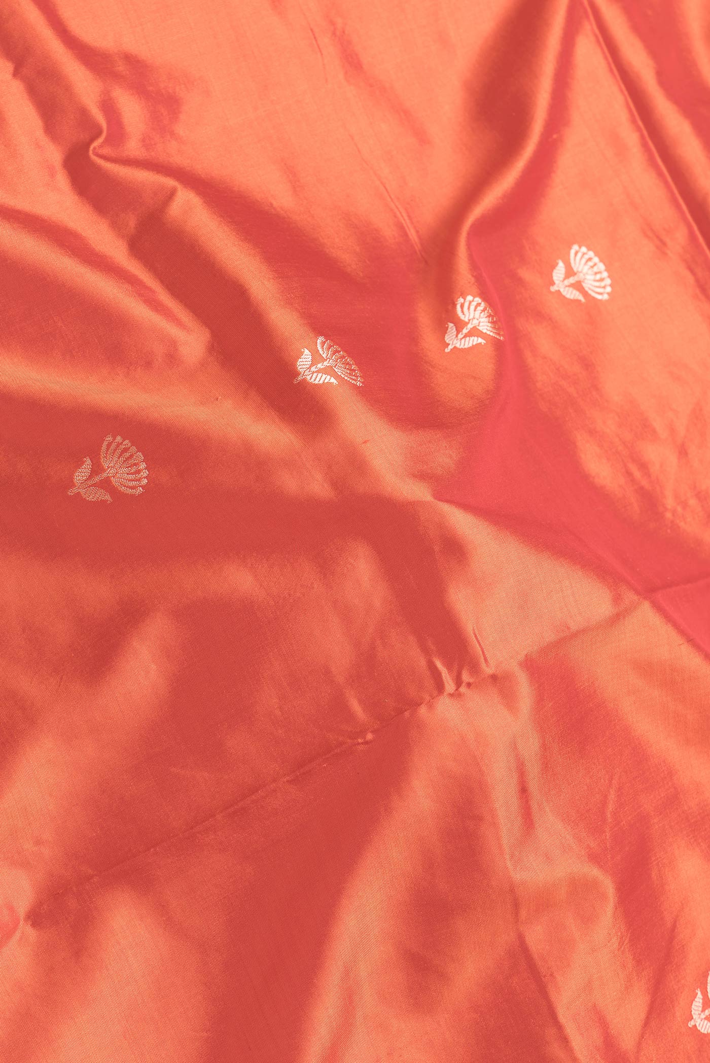 Close up of Orange Dual Tone Banarasi Silk Saree with Thread Butta on the body and Thread Border.  displaying folds