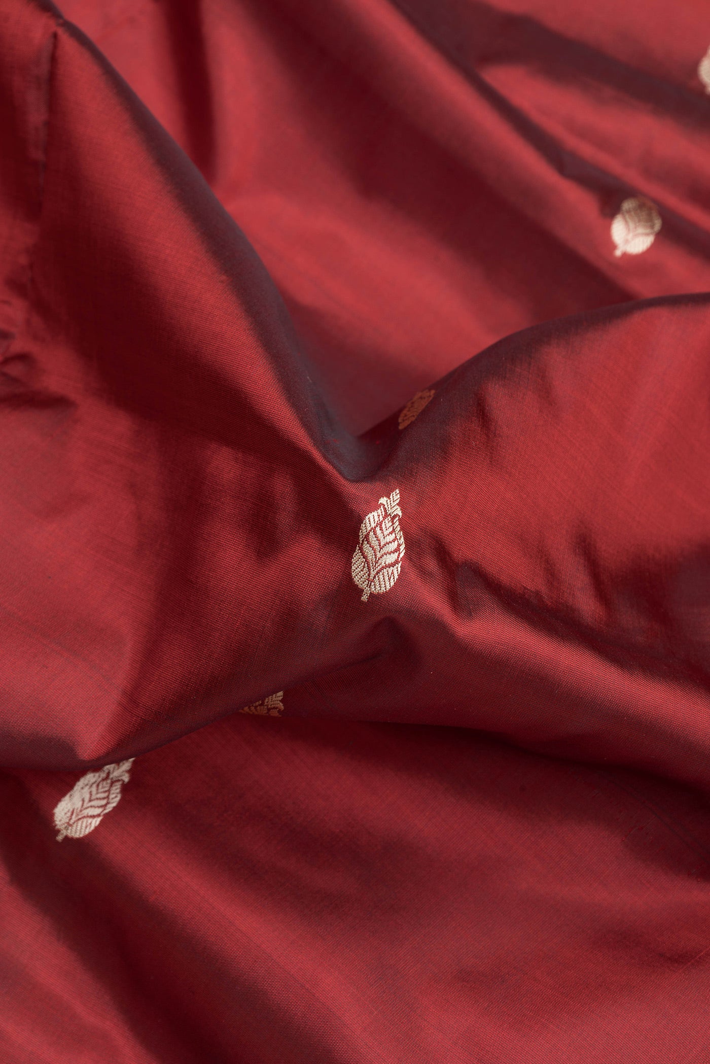 Close up of Maroon Dual Tone Banarasi Silk Saree with Thread Butta on the body and Thread Border.  displaying folds