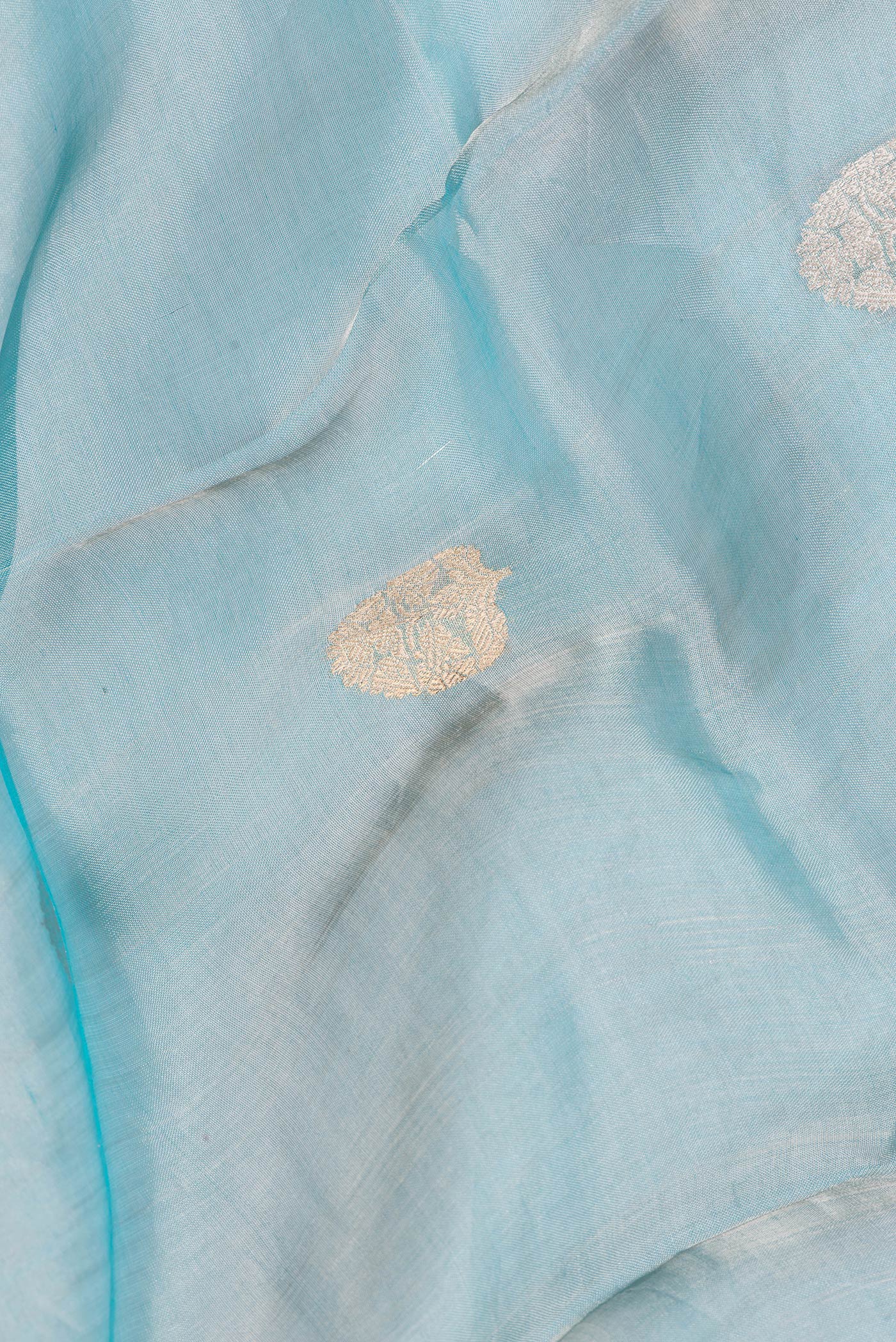 Close up of Sky Blue Dual Tone Organza Silk Saree with Zari Butta on the body and Zari Border.  displaying folds