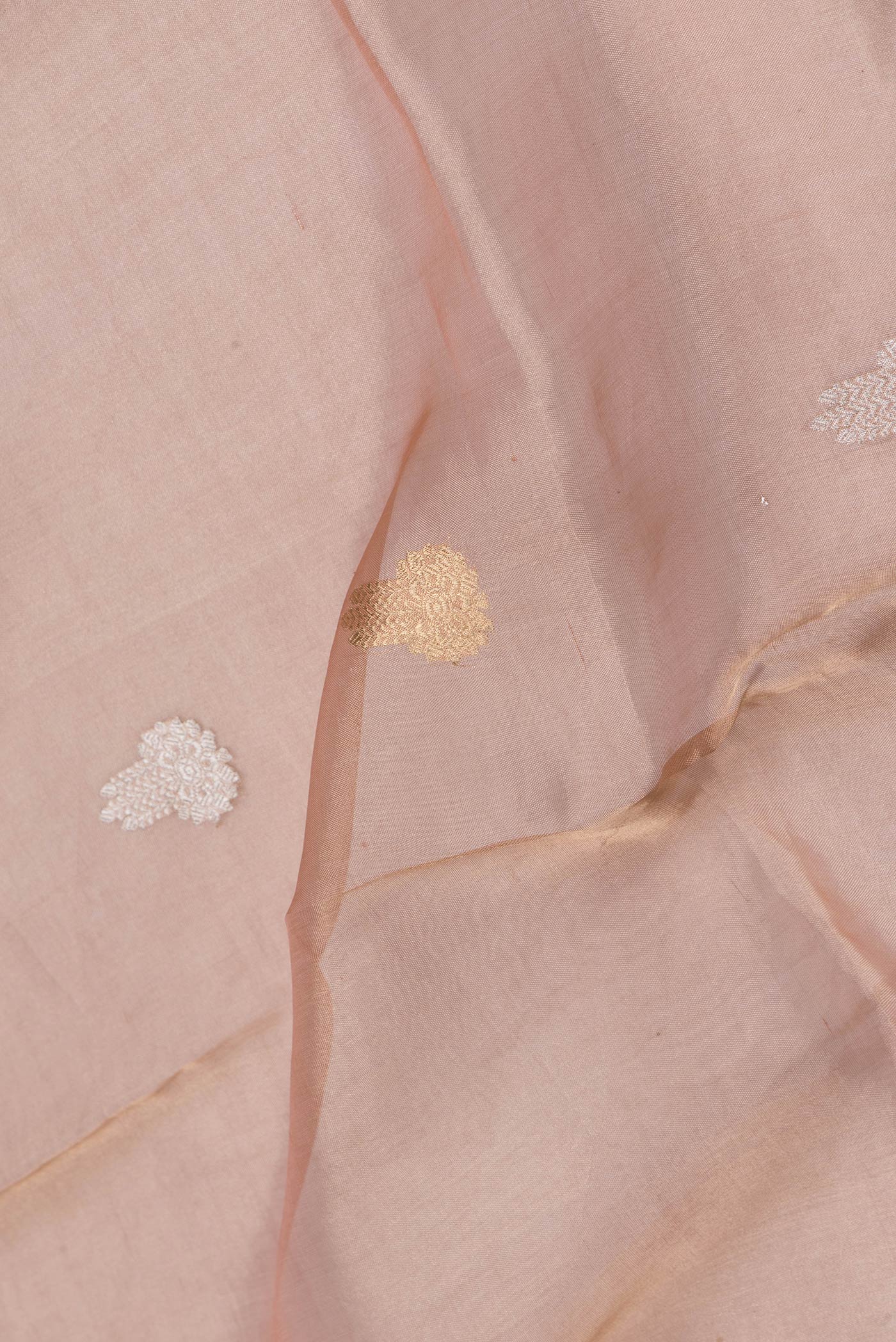 Close up of Rose Gold Dual Tone Organza Silk Saree with Zari Butta on the body and Zari Border.  displaying folds