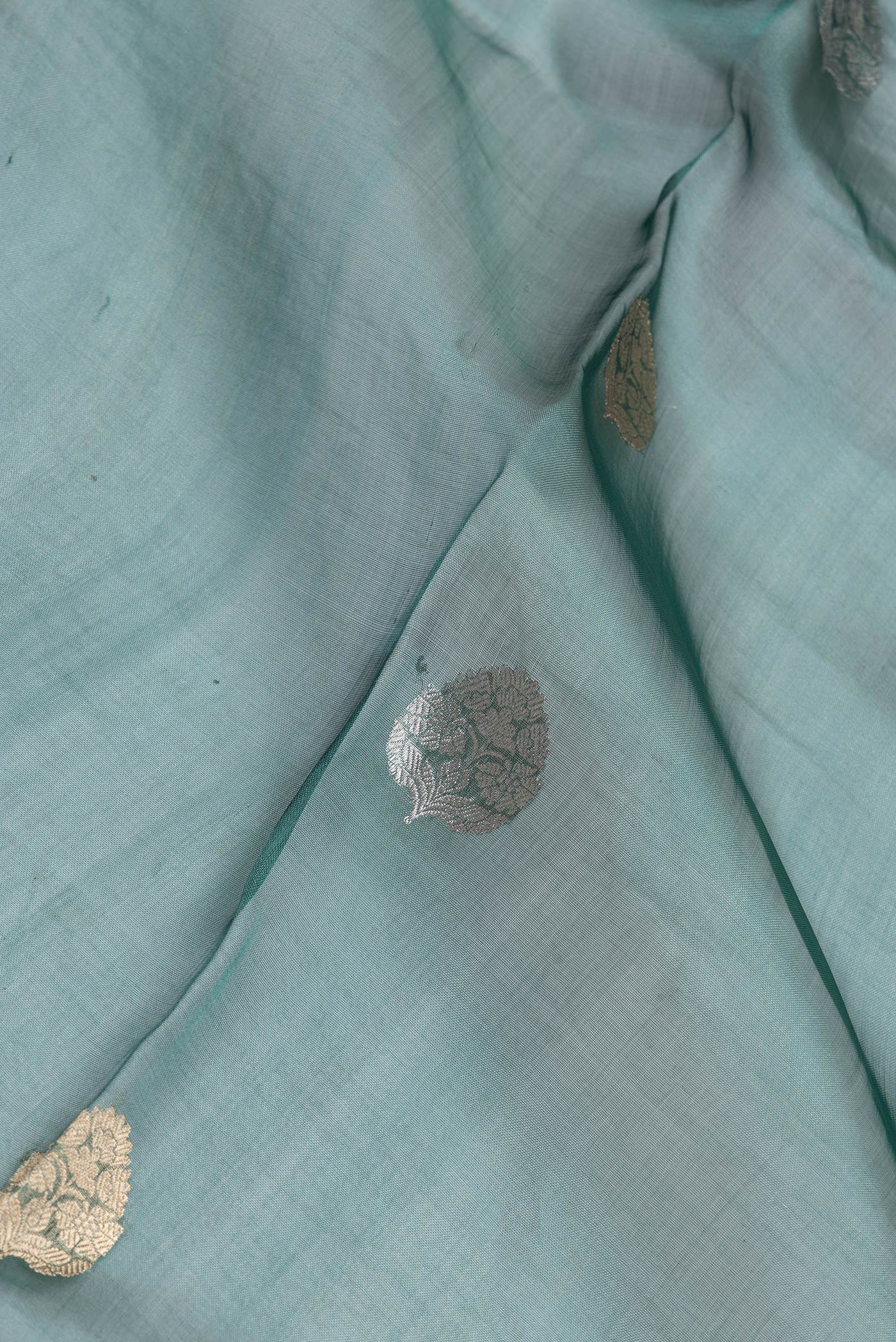 Close up of Peacock Blue Dual Tone Organza Silk Saree with Zari Butta on the body and Zari Border.  displaying folds