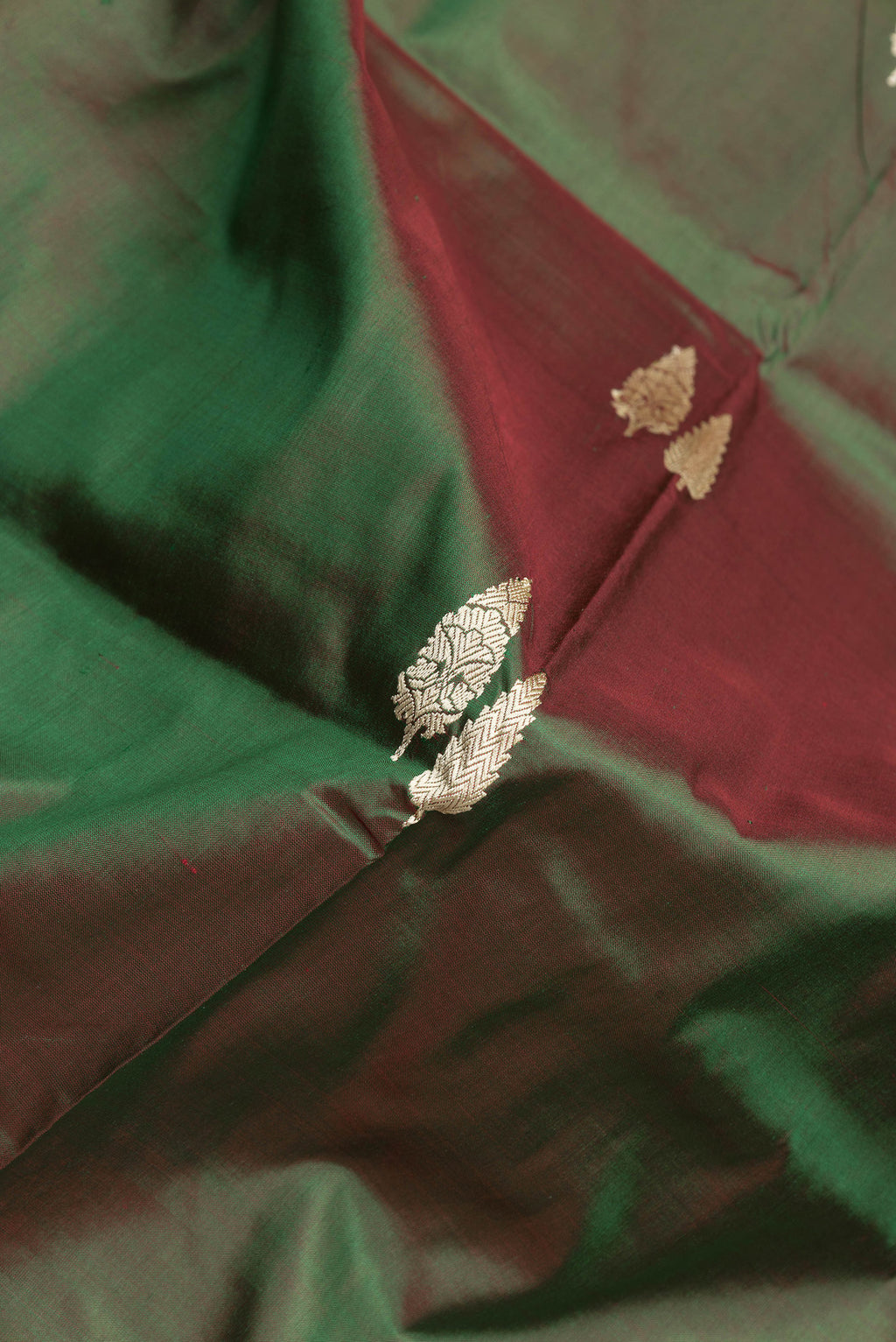 Close up of Green Dual Tone Banarasi Silk Saree with Thread Butta on the body and Thread Border.  displaying folds