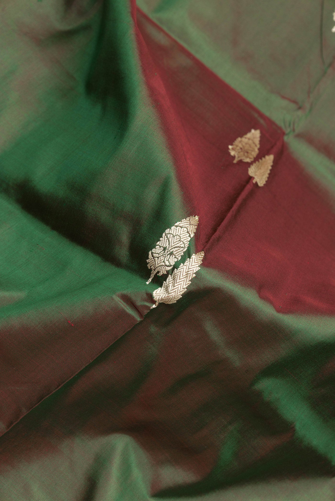 Close up of Green Dual Tone Banarasi Silk Saree with Thread Butta on the body and Thread Border.  displaying folds