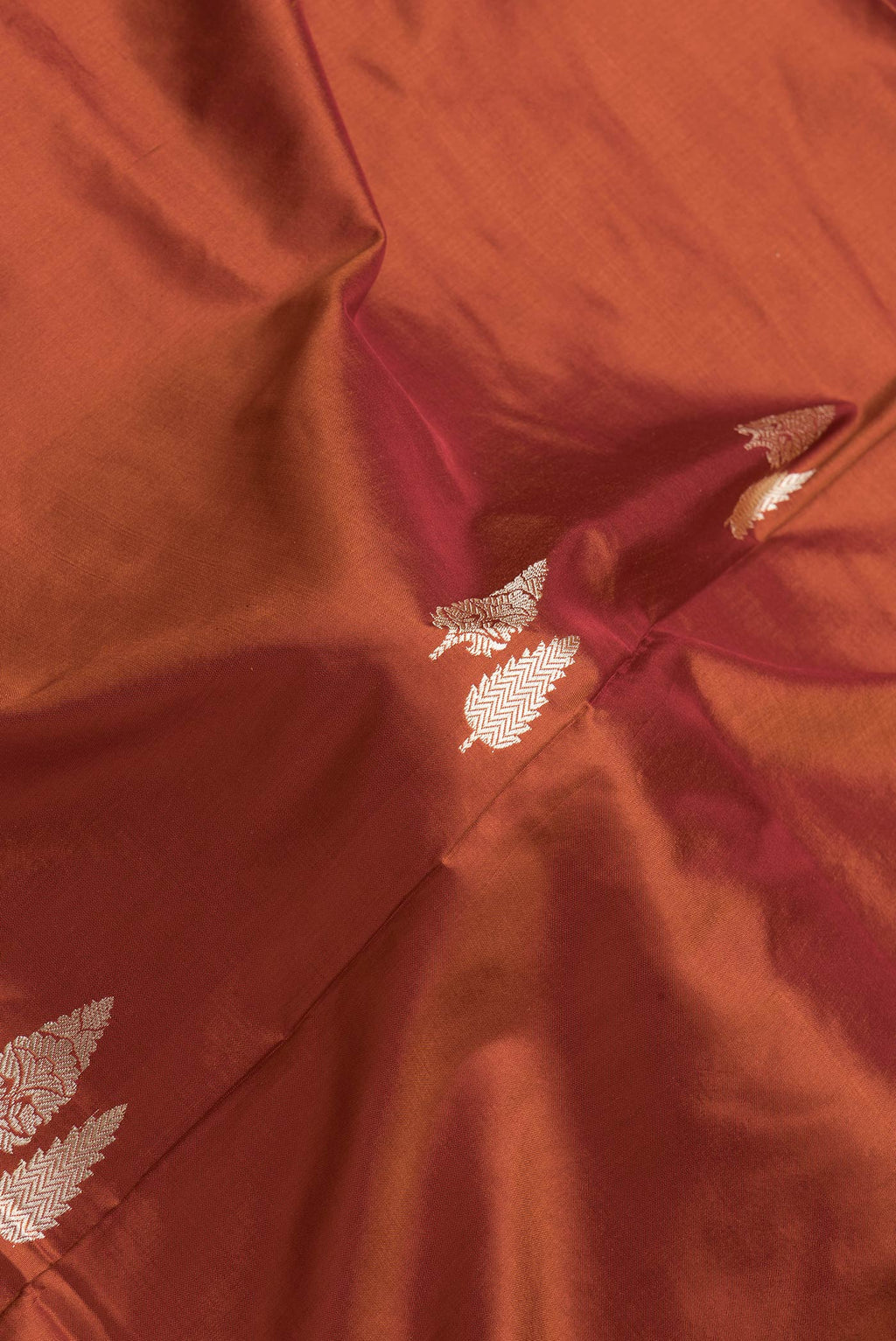 Close up of Orange Dual Tone Banarasi Silk Saree with Thread Butta on the body and Thread Border.  displaying folds