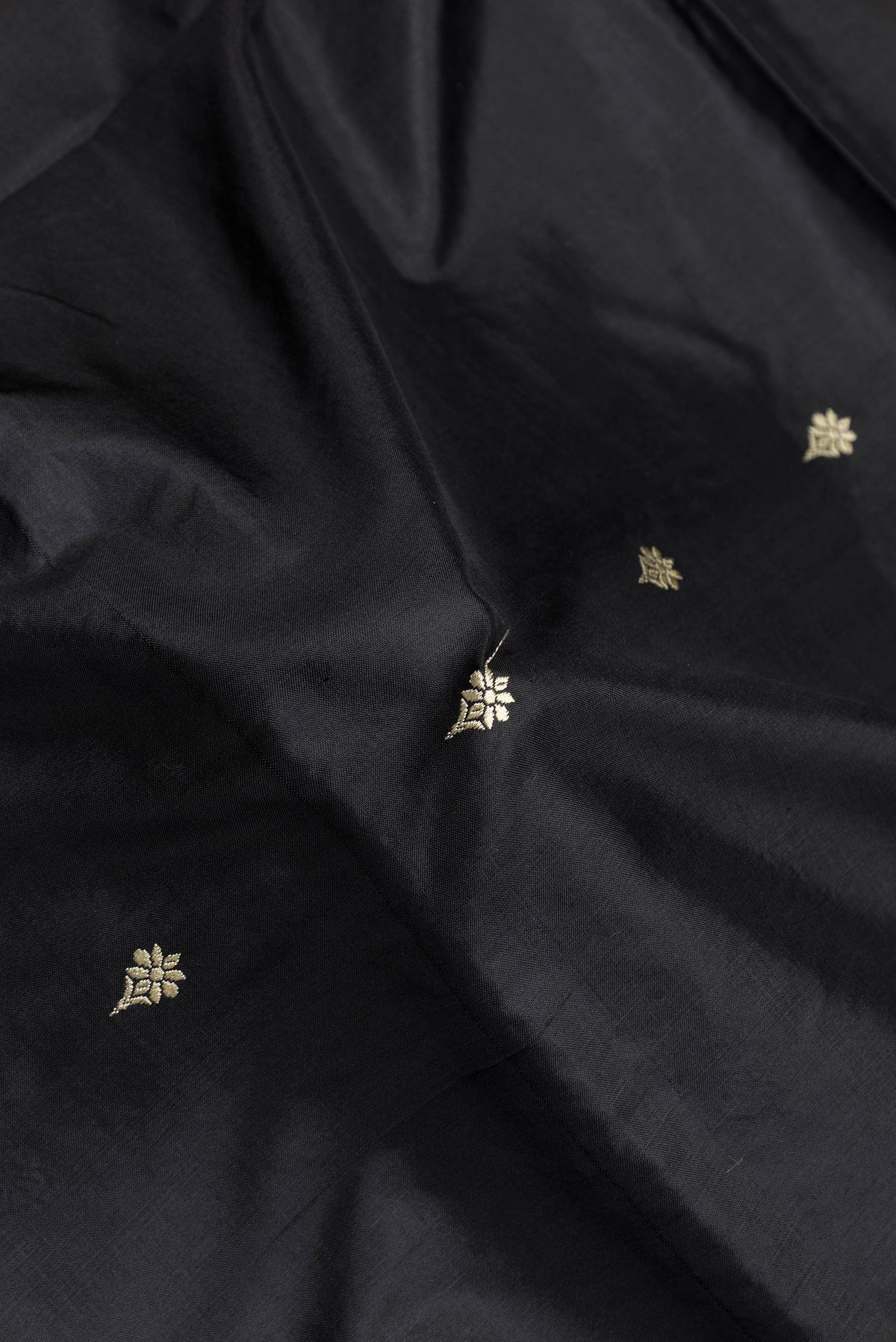 Close up of Black Dual Tone Banarasi Silk Saree with Thread Butta on the body and Thread Border.  displaying folds