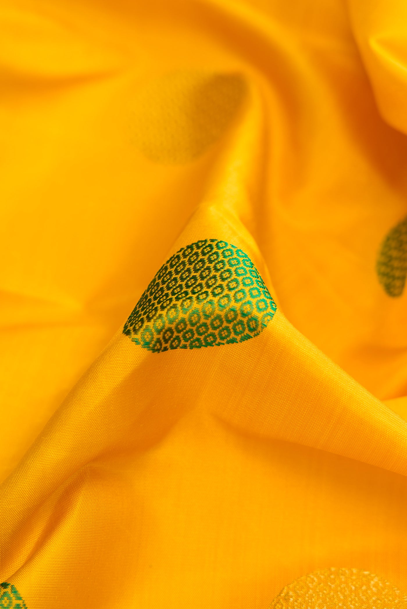 Close up of Pure Silk Pure Zari Yellow Dual Tone Kanchipuram Saree with Zari And Thread Butta on the body and Fancy Border.  displaying folds