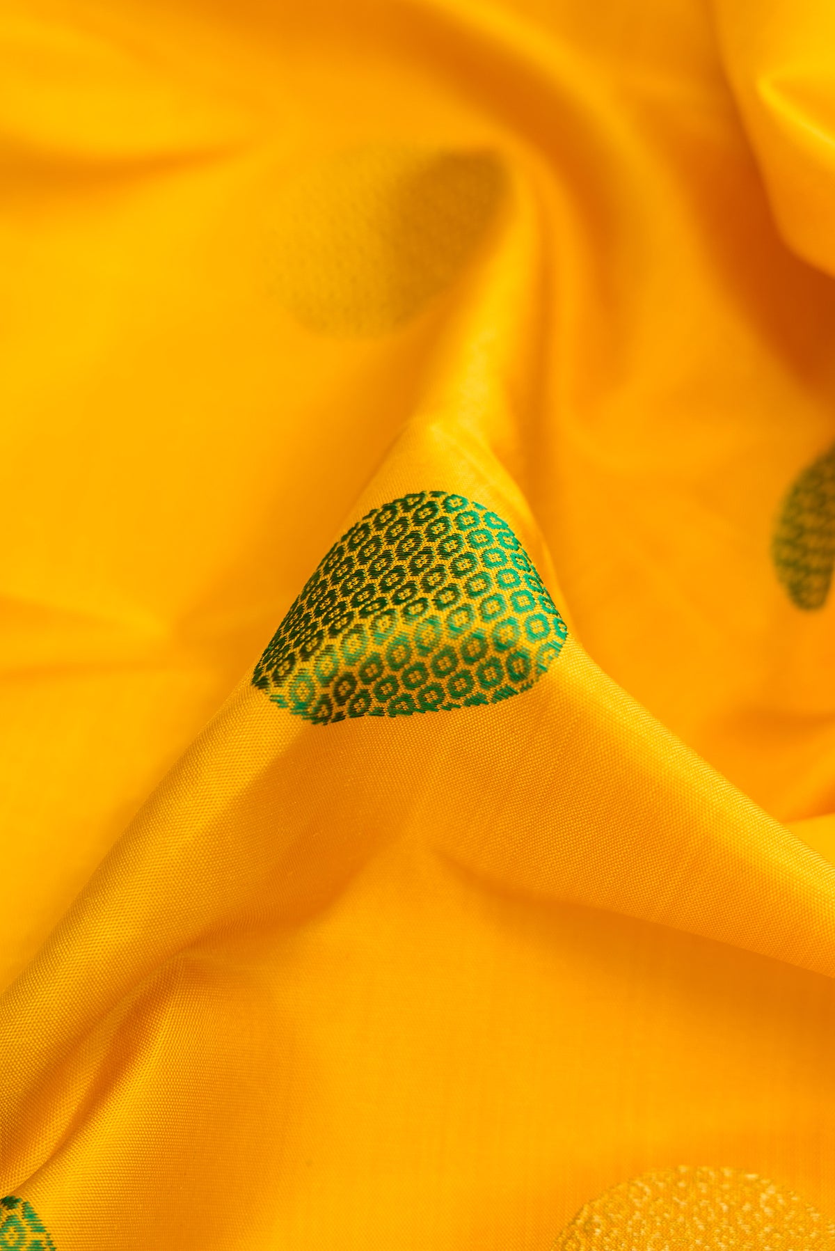 Close up of Pure Silk Pure Zari Yellow Dual Tone Kanchipuram Saree with Zari And Thread Butta on the body and Fancy Border.  displaying folds
