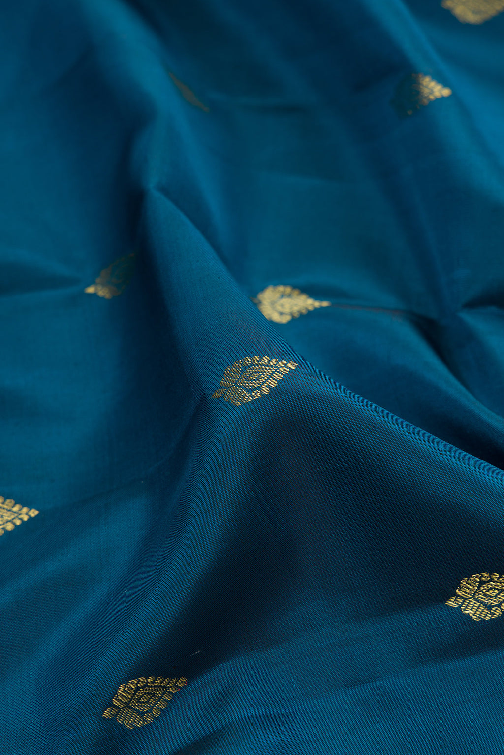 Close up of Peacock Blue Kanchipuram Silk Saree with Zari Butta on the body and Zari Border.  displaying folds