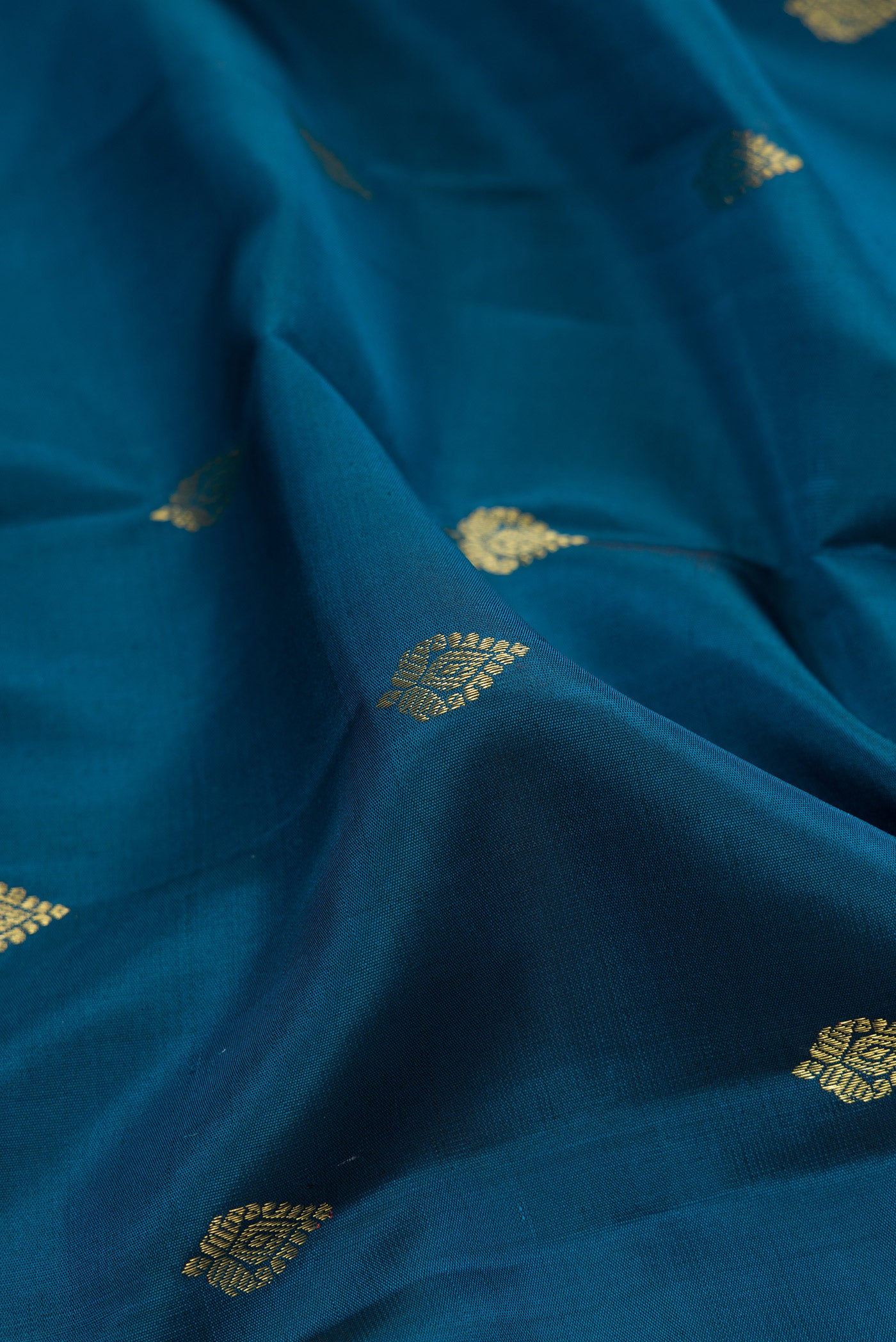 Close up of Peacock Blue Kanchipuram Silk Saree with Zari Butta on the body and Zari Border.  displaying folds