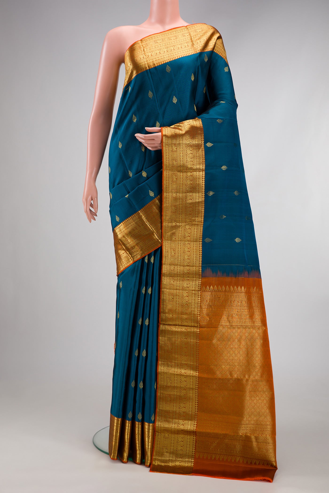 Peacock Blue Kanchipuram Silk Saree with Zari Butta on the body and Zari Border.  displayed on a mannequin