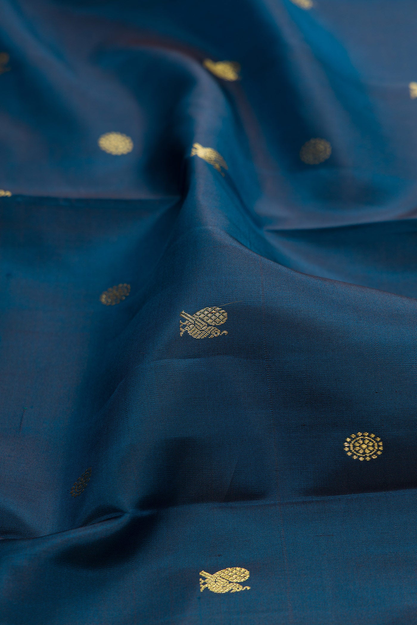 Close up of Peacock Blue Kanchipuram Silk Saree with Zari Butta on the body and Zari Border.  displaying folds