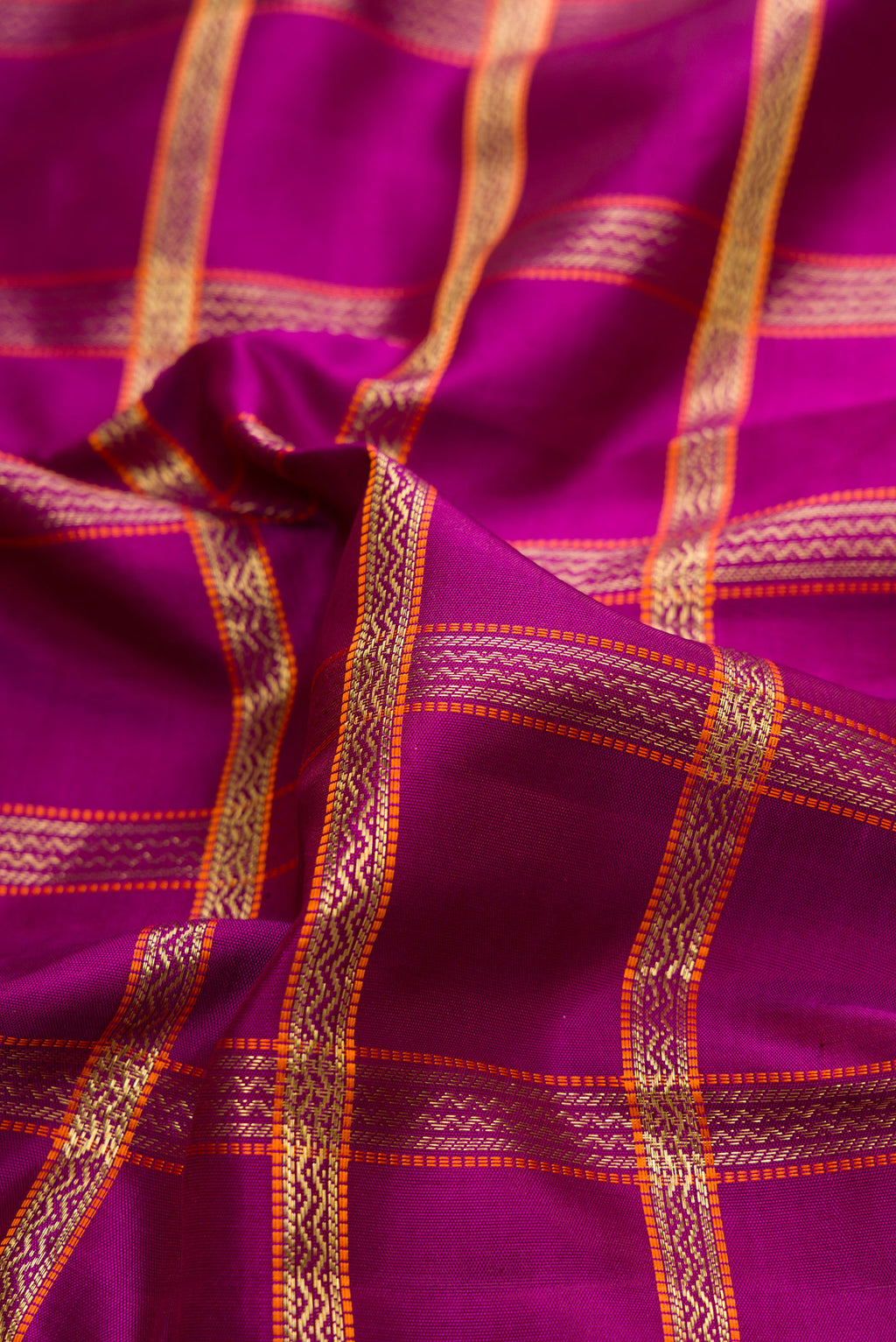 Close up of Pure Silk Pure Zari Magenta Dual Tone Kanchipuram Saree with Checked design on the body and Zari Border.  displaying folds