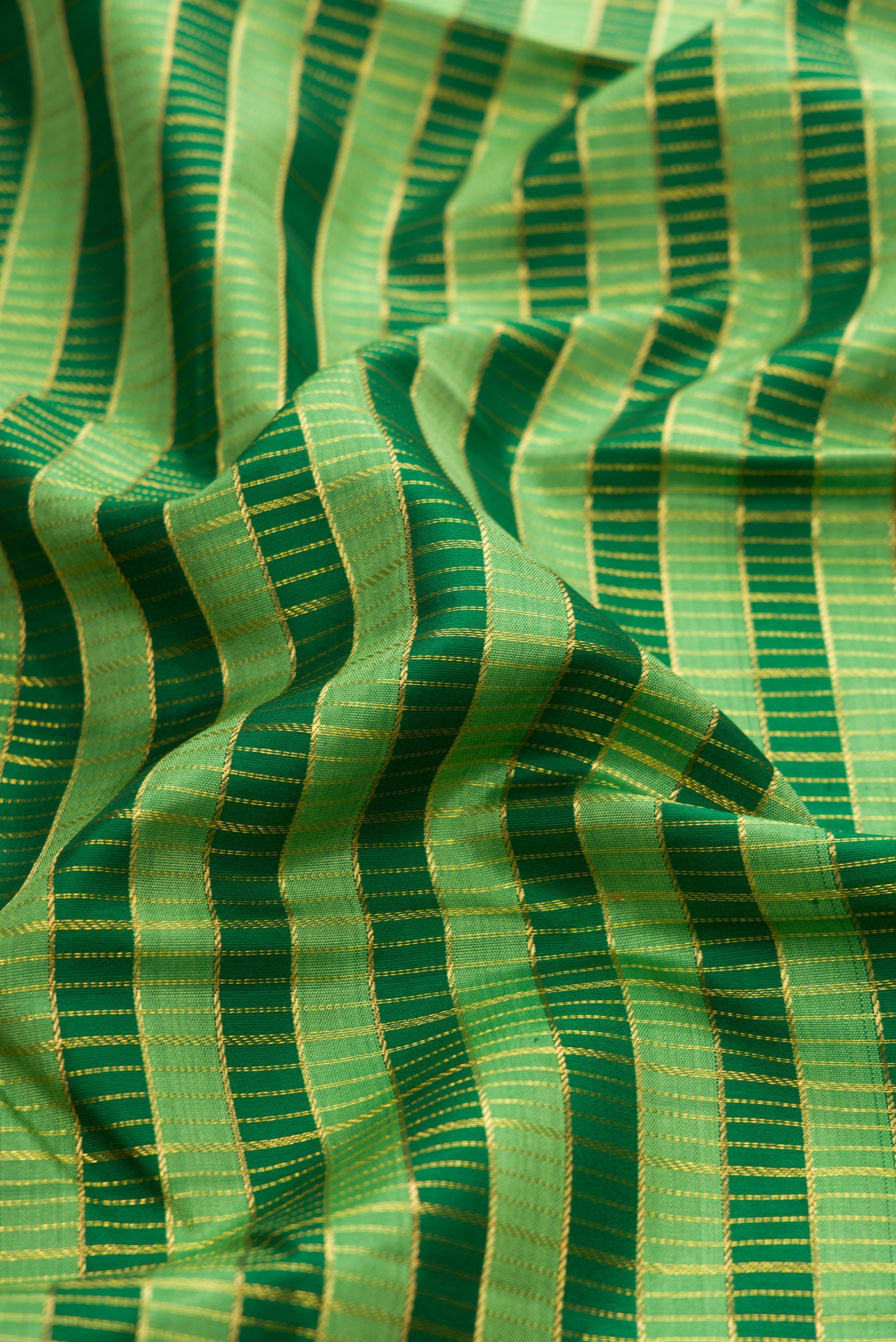 Close up of Green Kanchipuram Silk Saree with Stripes on the body and Zari Border.  displaying folds