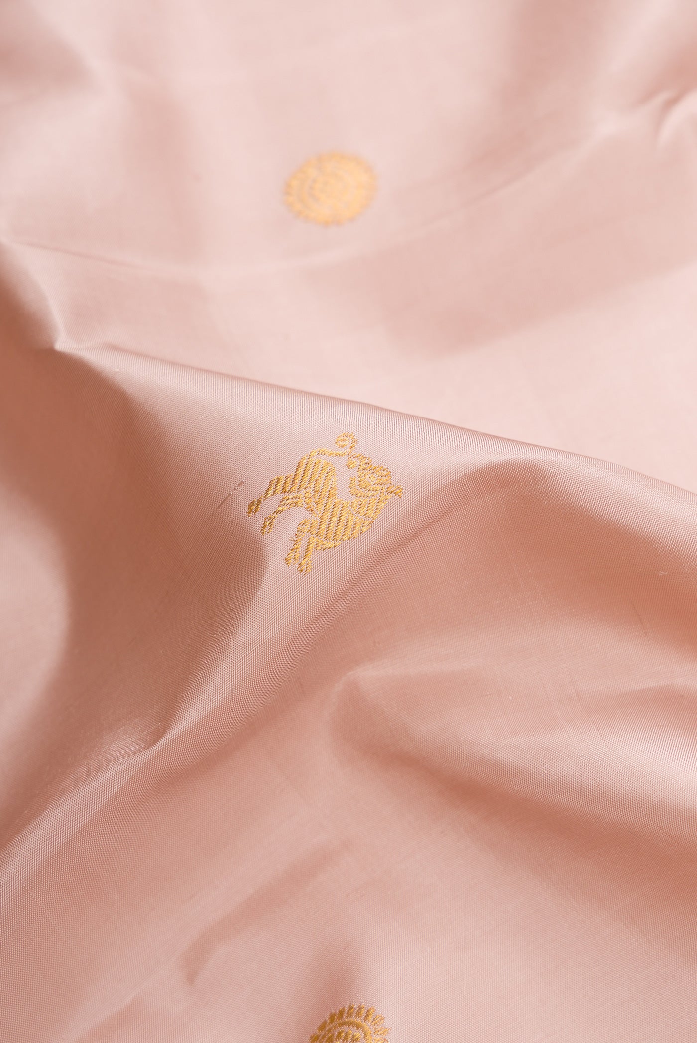 Close up of Rose Gold Dual Tone Kanjivaram Silk Saree with Zari Butta on the body and Fancy Border.  displaying folds