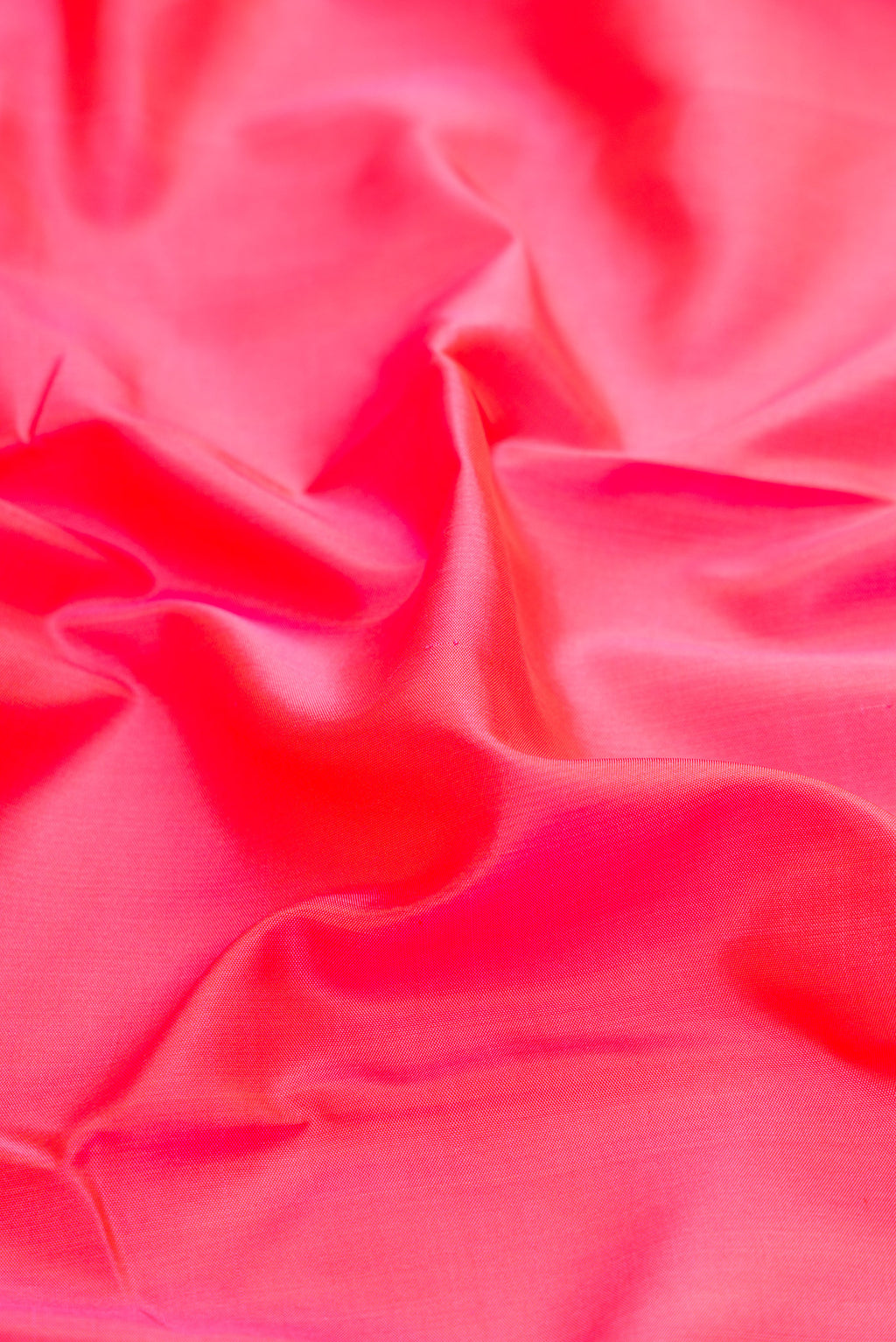 Close up of Coral Kanchipuram Silk Saree with Plain Body and Zari Border.  displaying folds