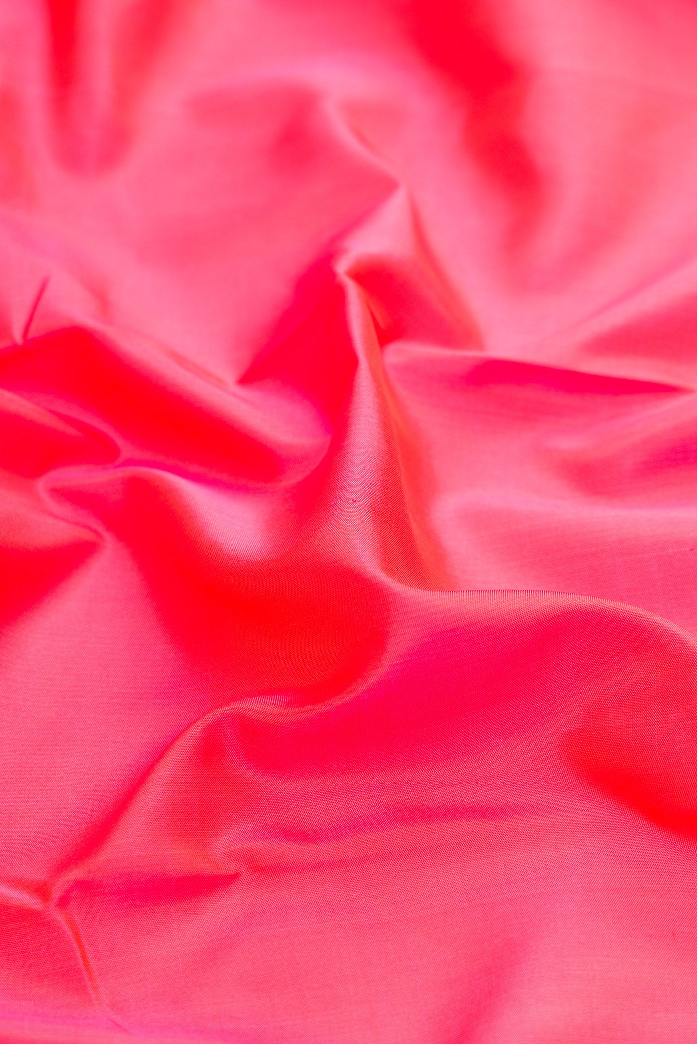 Close up of Coral Kanchipuram Silk Saree with Plain Body and Zari Border.  displaying folds
