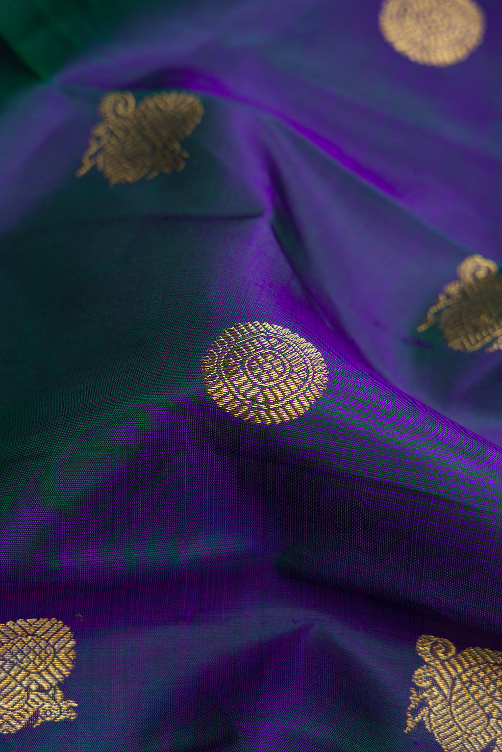 Close up of Pure Silk Pure Zari Peacock Blue Dual Tone Kanjivaram Saree with Zari Butta on the body and Zari Border.  displaying folds