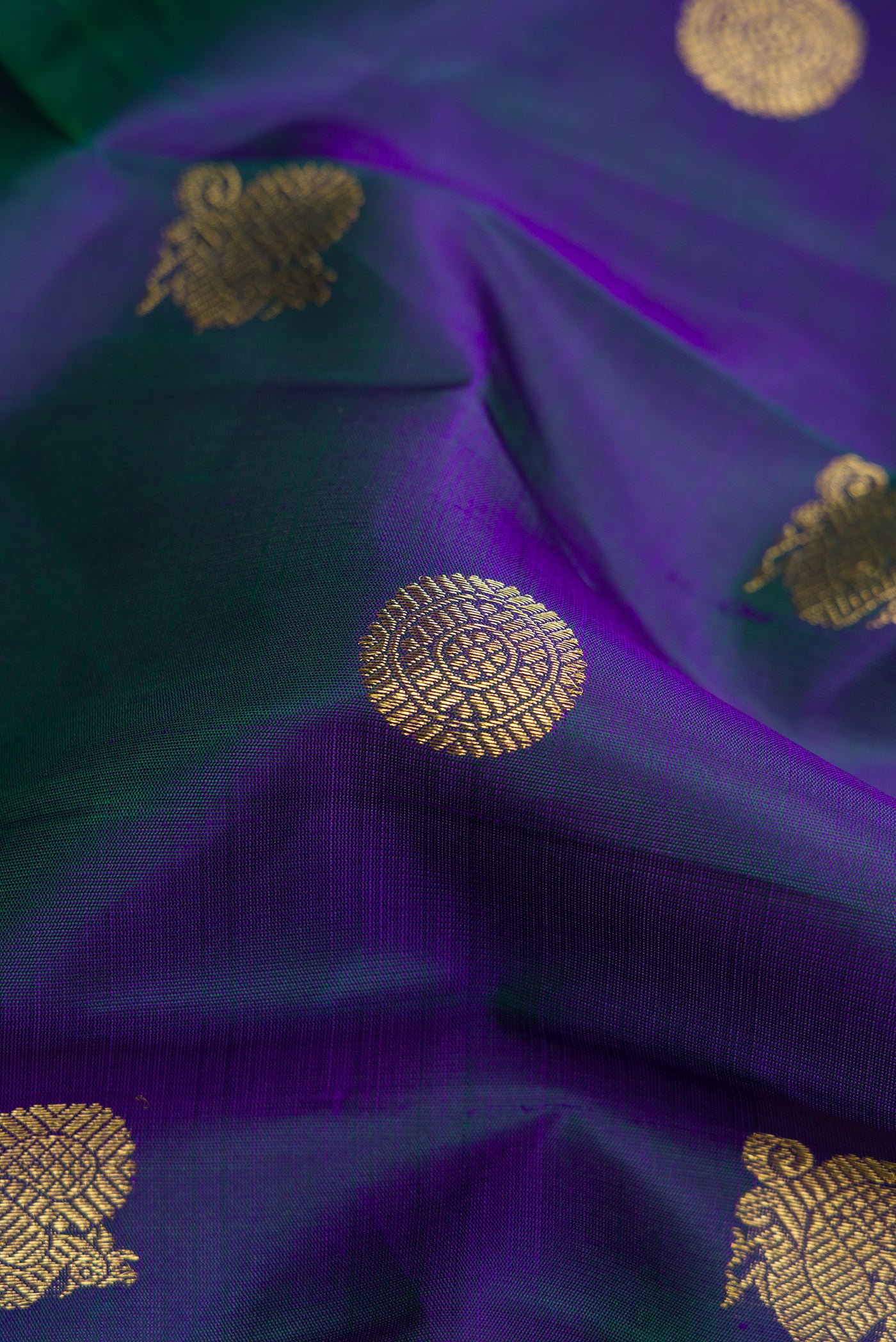 Close up of Pure Silk Pure Zari Peacock Blue Dual Tone Kanjivaram Saree with Zari Butta on the body and Zari Border.  displaying folds
