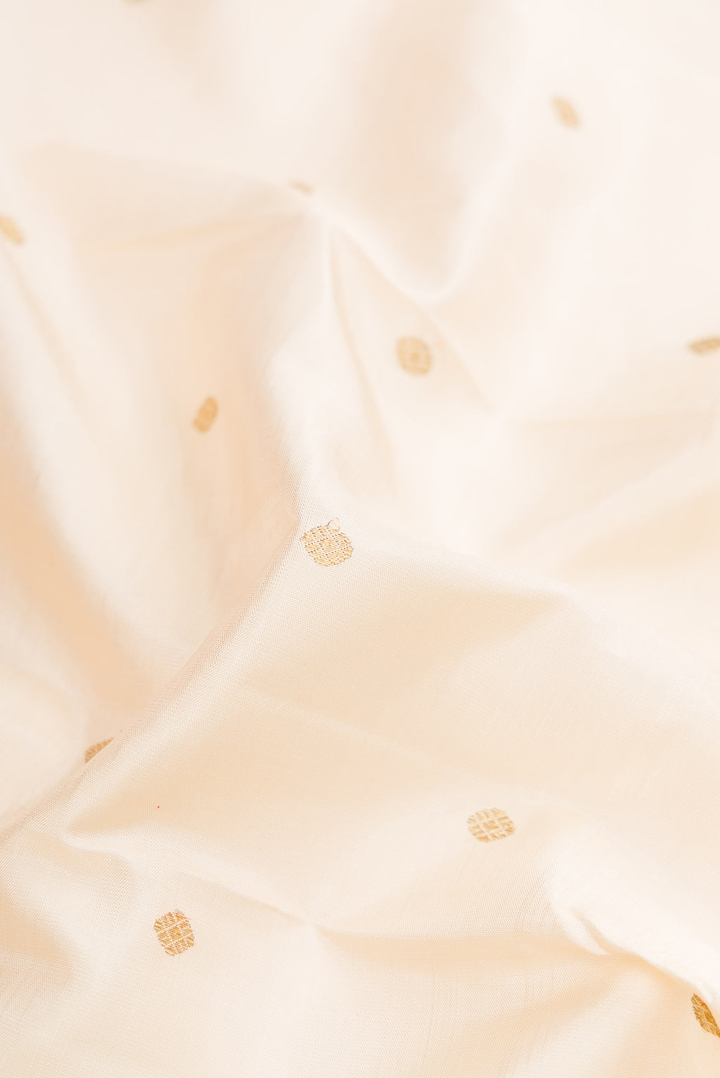 Close up of Pure Silk Pure Zari Off White Dual Tone Kanjivaram Saree with Zari Butta on the body and Fancy Border.  displaying folds