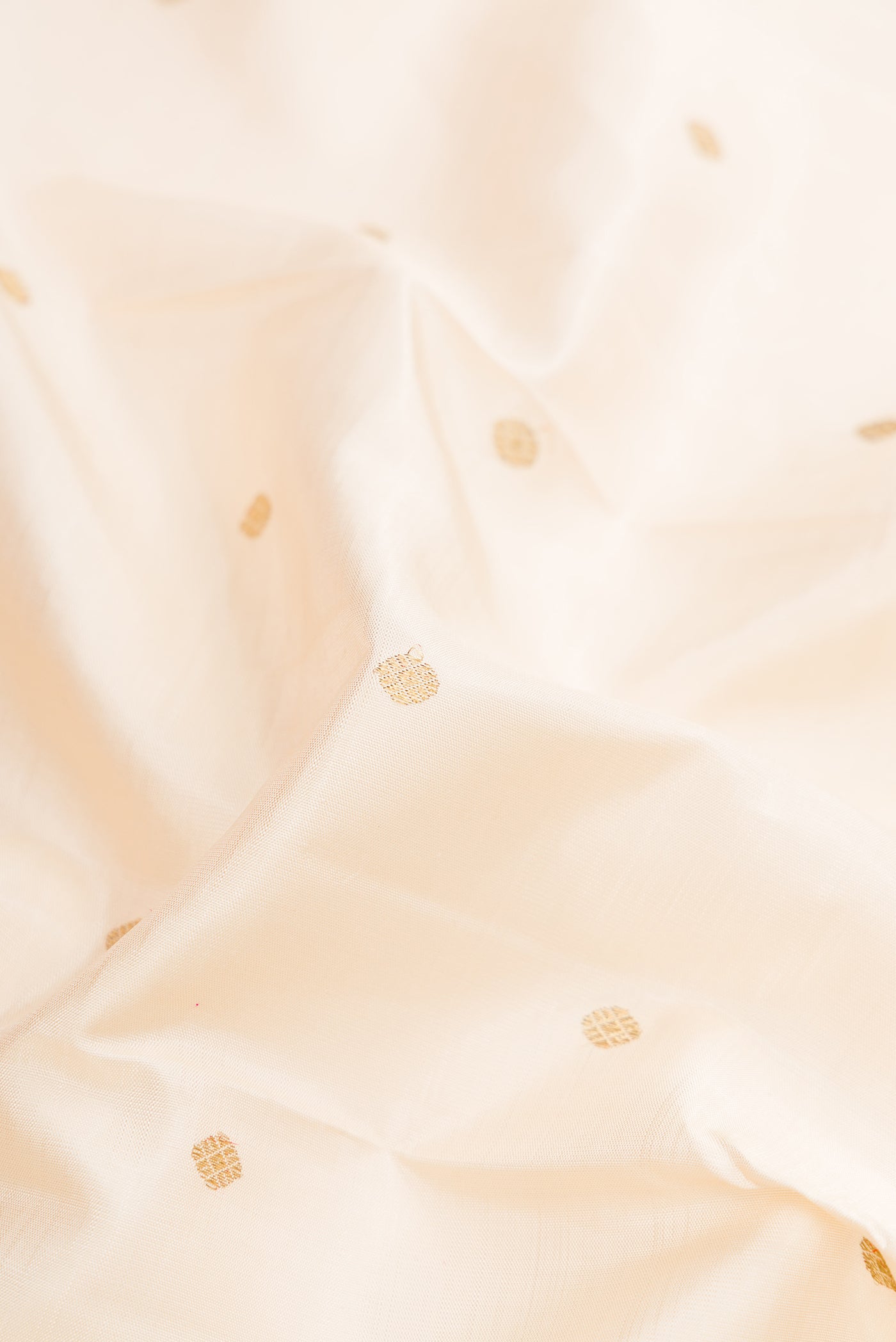 Close up of Pure Silk Pure Zari Off White Dual Tone Kanjivaram Saree with Zari Butta on the body and Fancy Border.  displaying folds