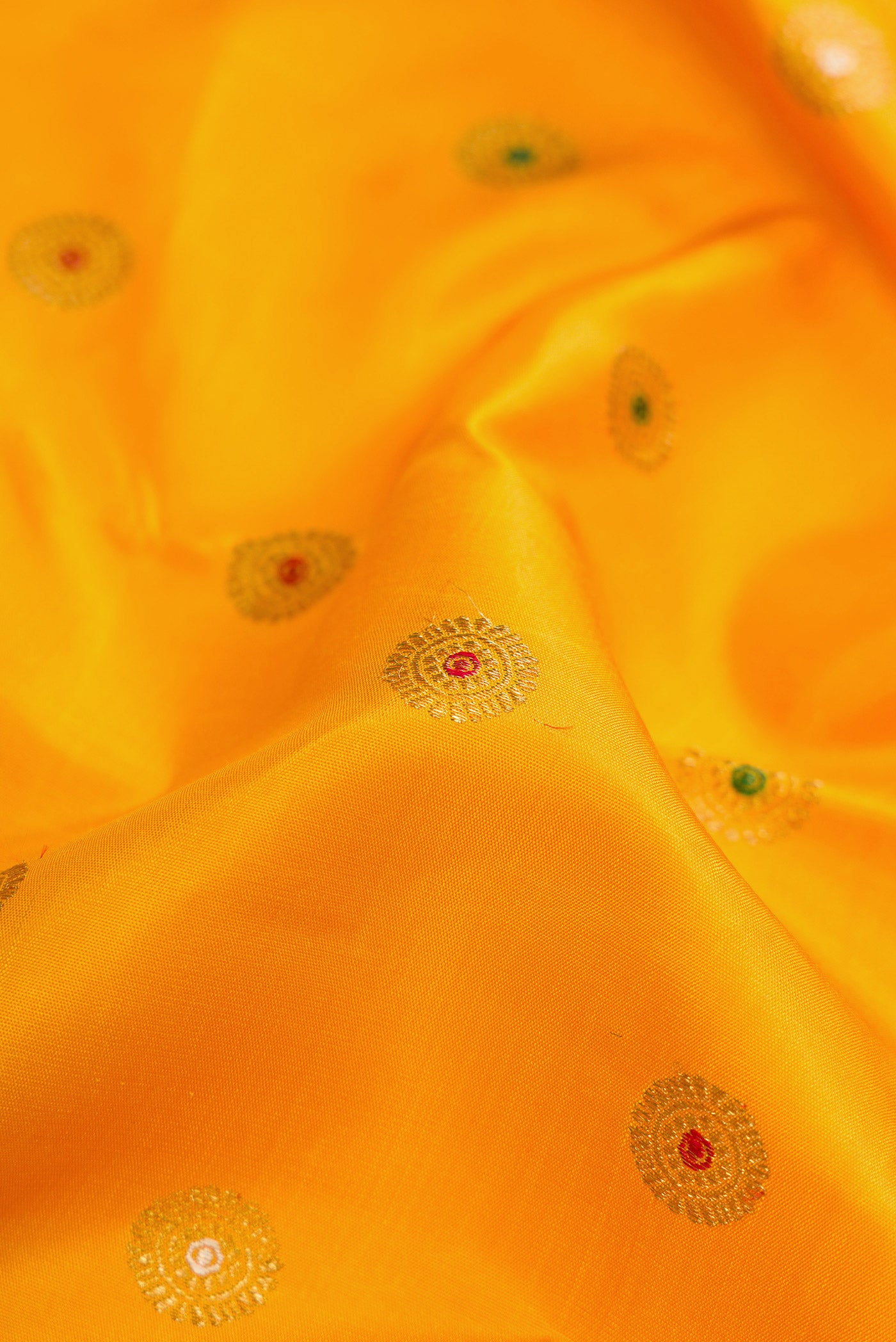 Close up of Pure Silk Pure Zari Mustard Dual Tone Kanjivaram Saree with Zari And Thread Butta on the body and Zari Border.  displaying folds